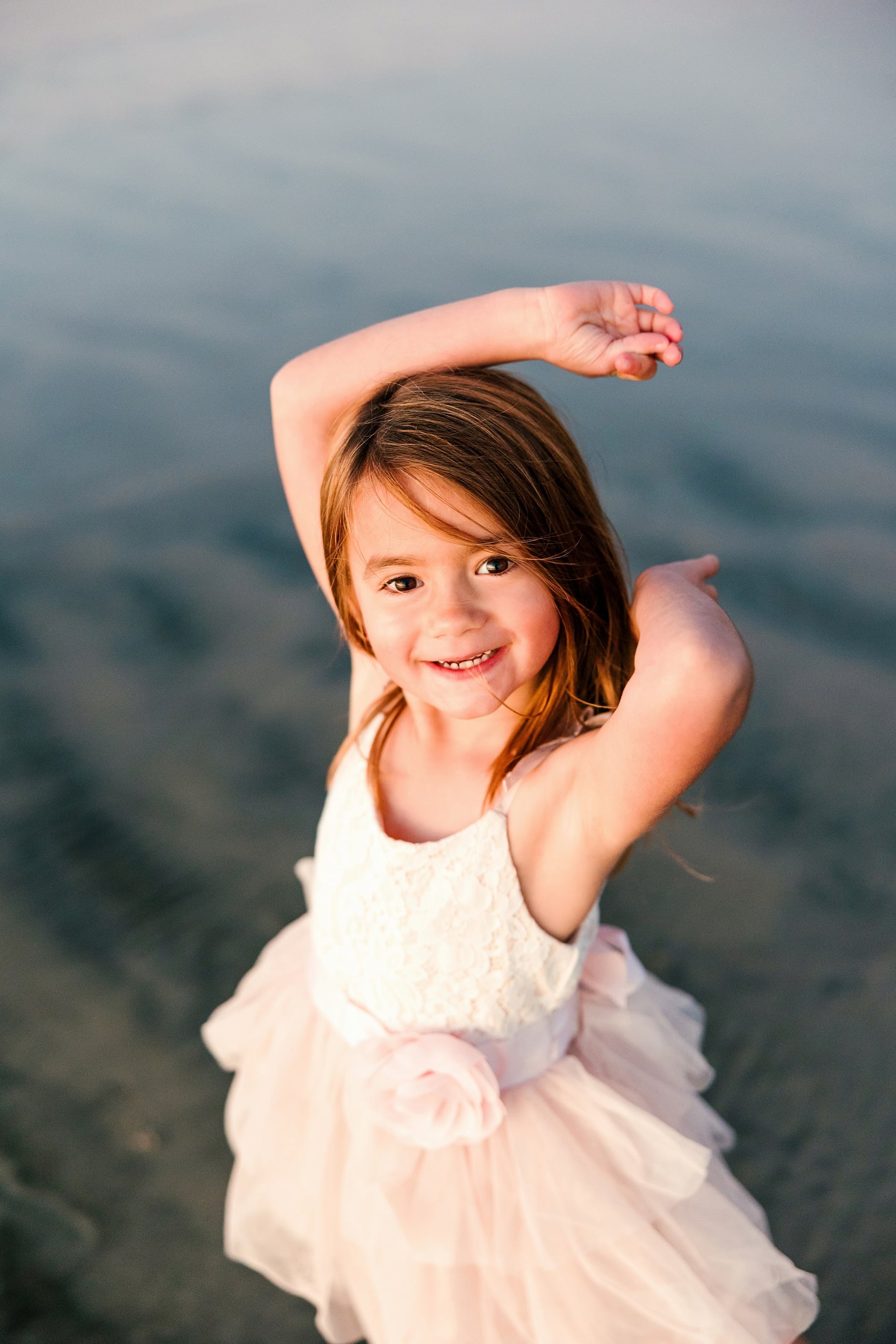 The Day the Sun Stood Still — 10 Young child in white and pink dress arms raised at Del Mar beach at golden hour