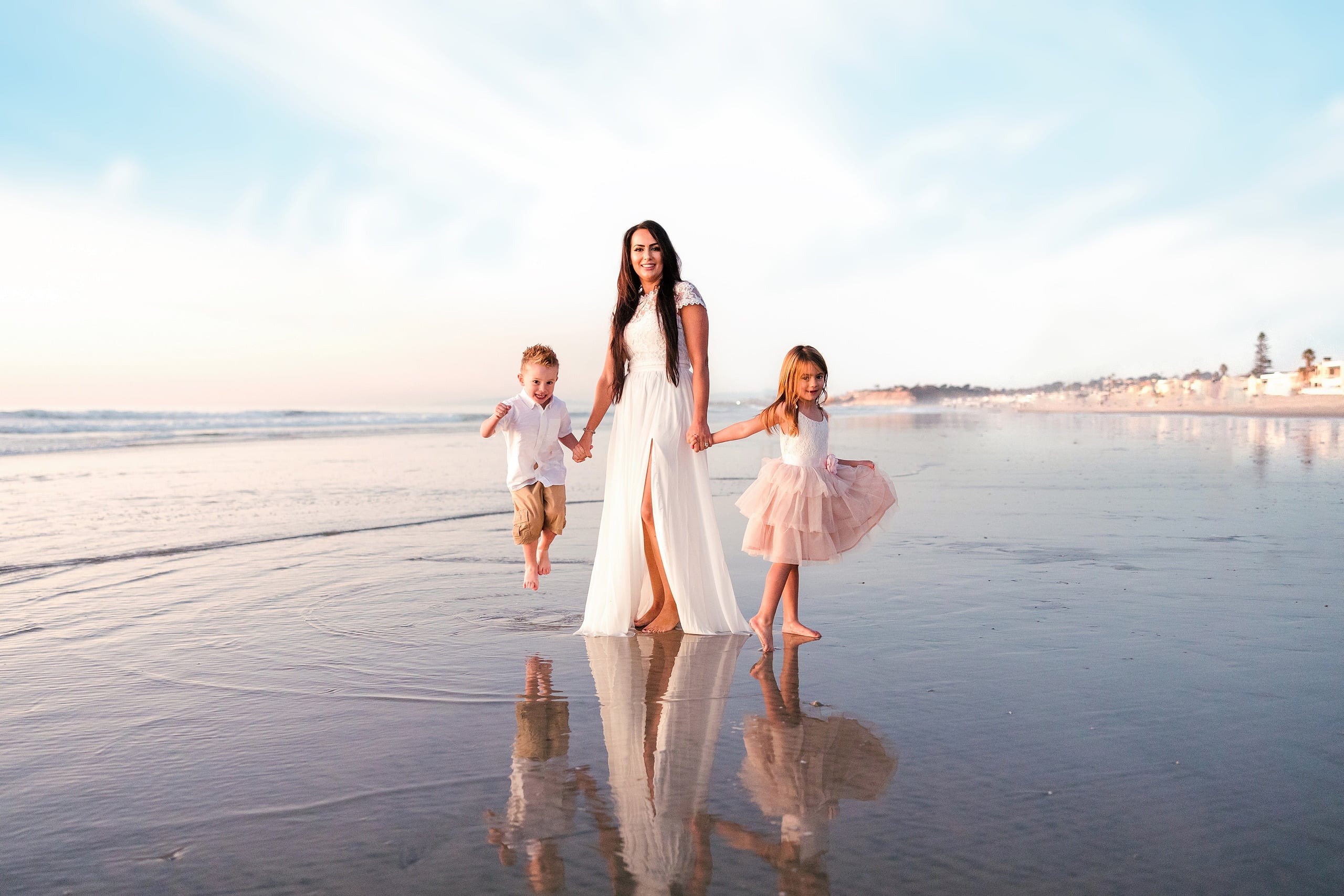 The Day the Sun Stood Still — 14 Woman in white dress holding hands with two children on wet beach sand