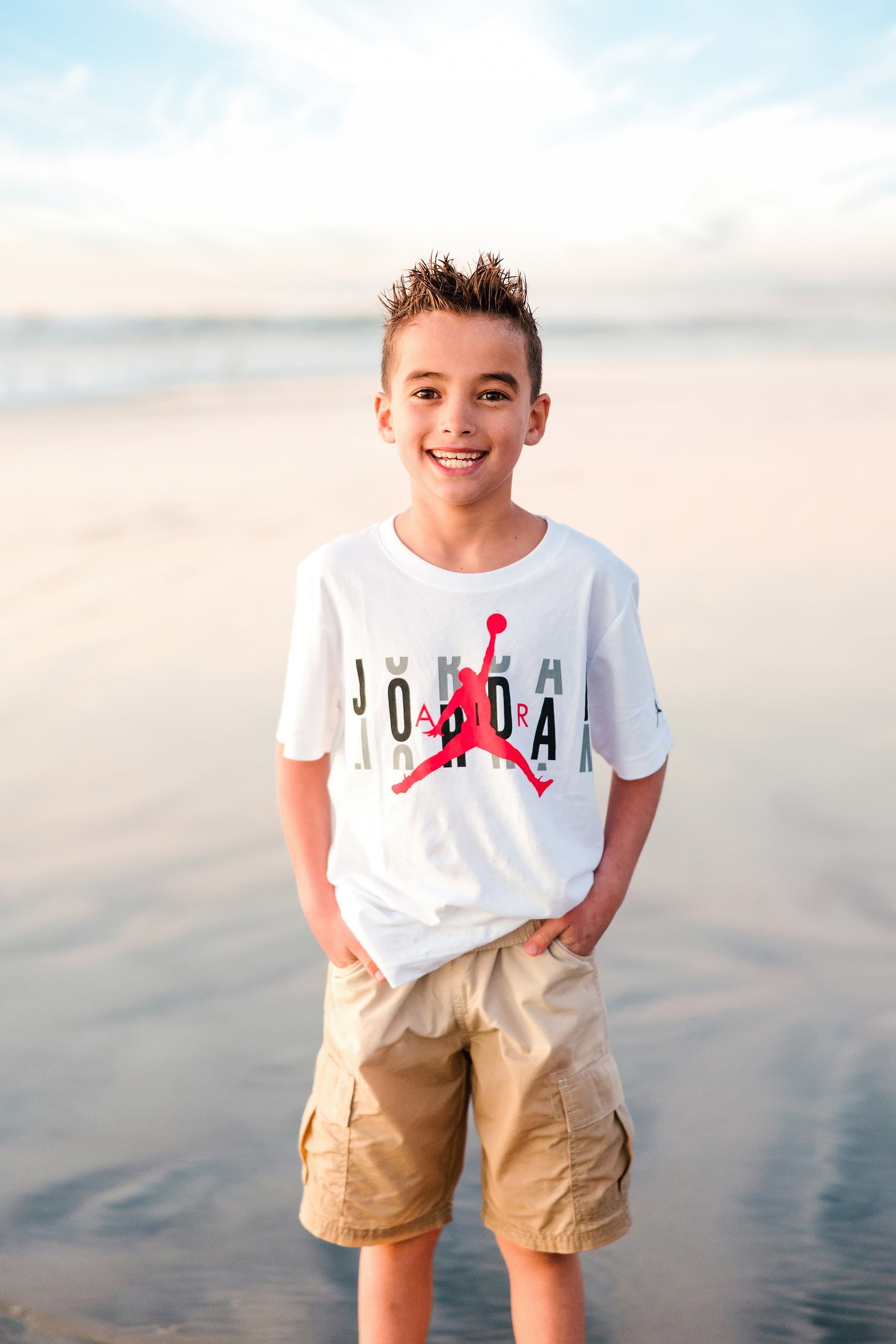 The Day the Sun Stood Still — 22 Child in white shirt and tan cargo shorts on wet beach sand at golden hour