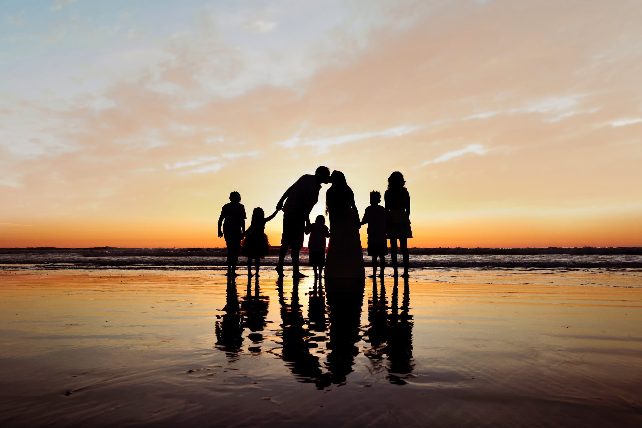 The Day the Sun Stood Still — 28 Family of seven in silhouette holding hands on wet beach sand at sunset