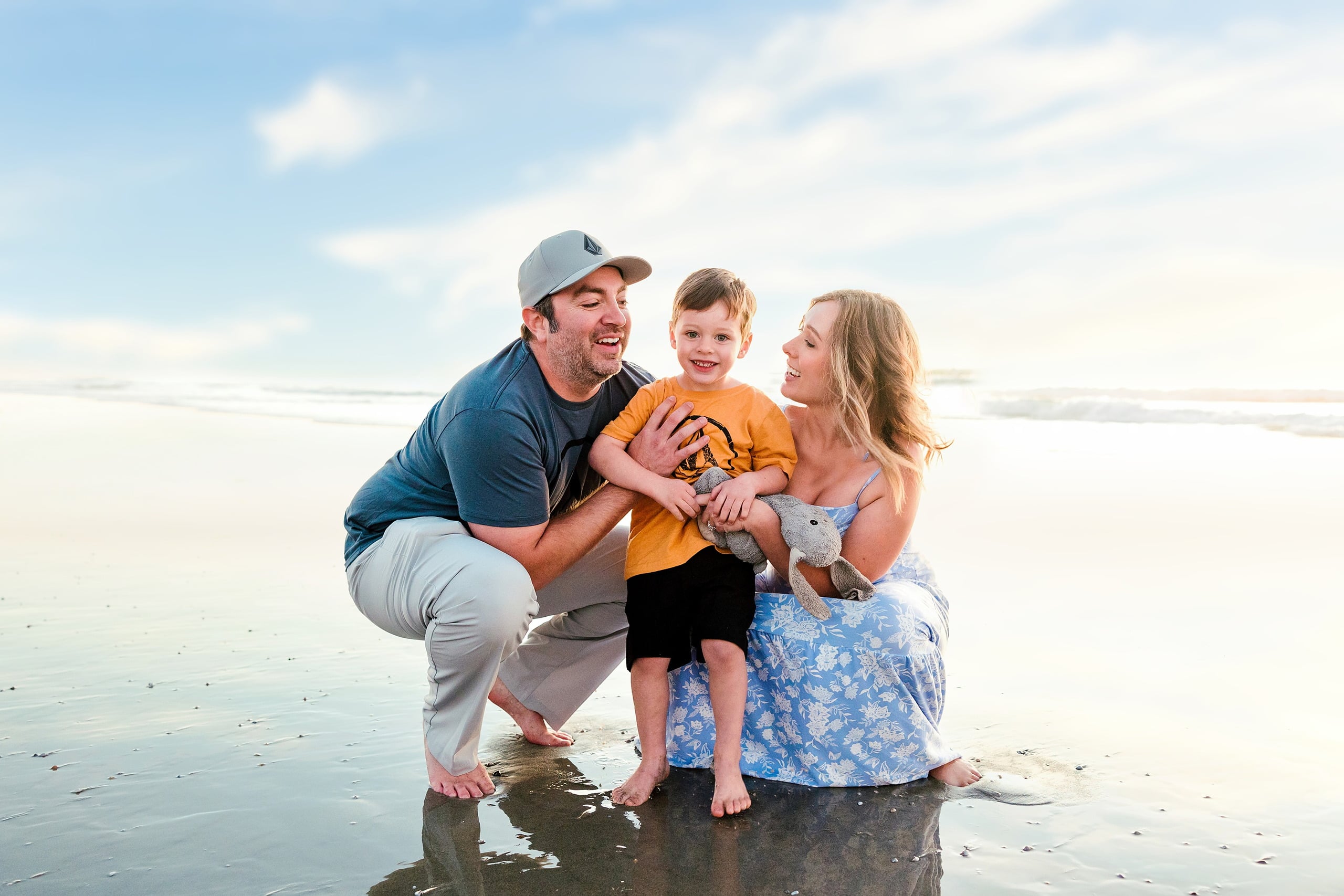 The Day the Sun Stood Still — 30 Man and woman standing with young child on wet beach sand at golden hour