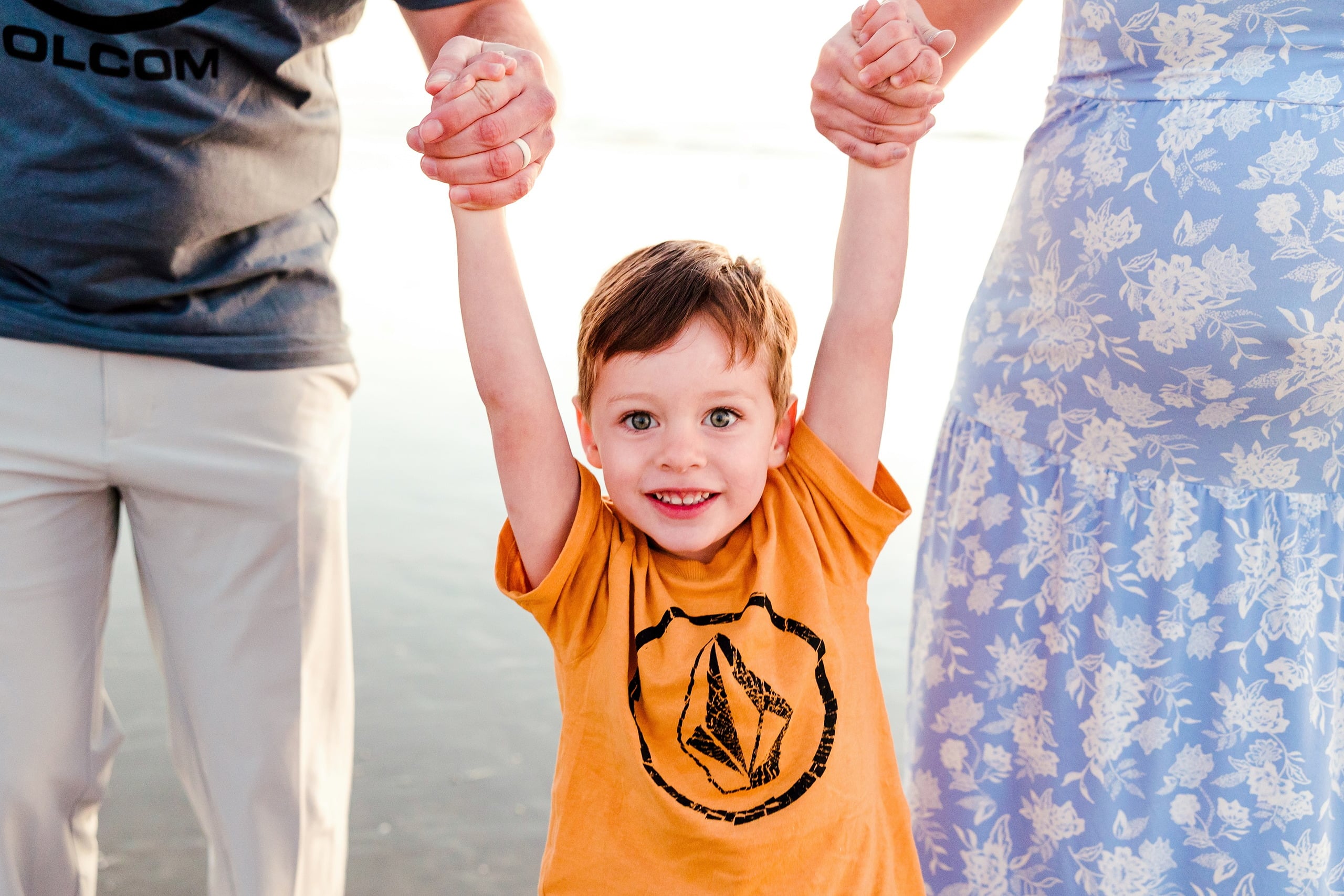 The Day the Sun Stood Still — 31 Close-up: child's arms held up by two parents on beach at Del Mar