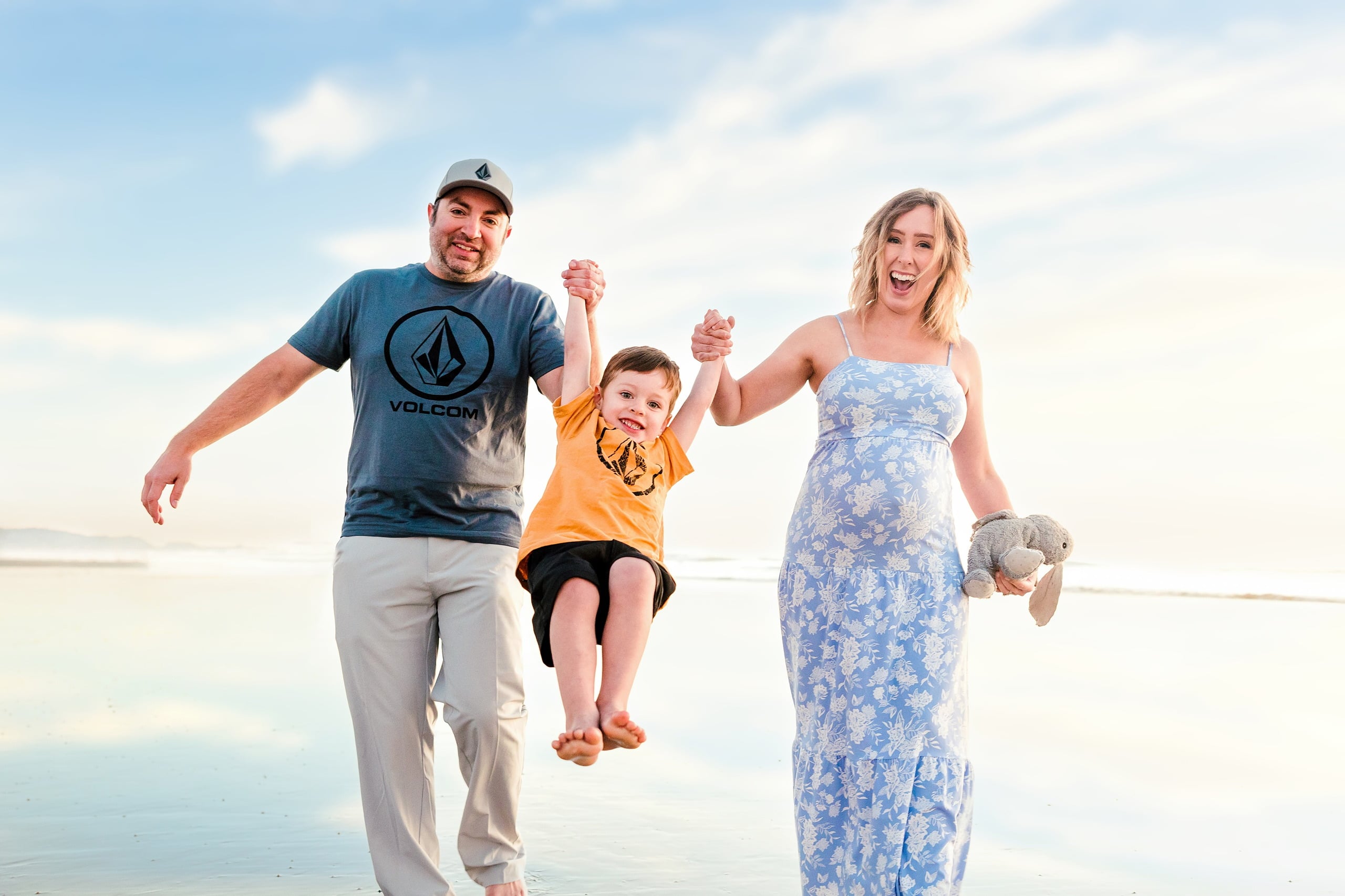 The Day the Sun Stood Still — 32 Man and woman holding hands swinging toddler on wet beach sand