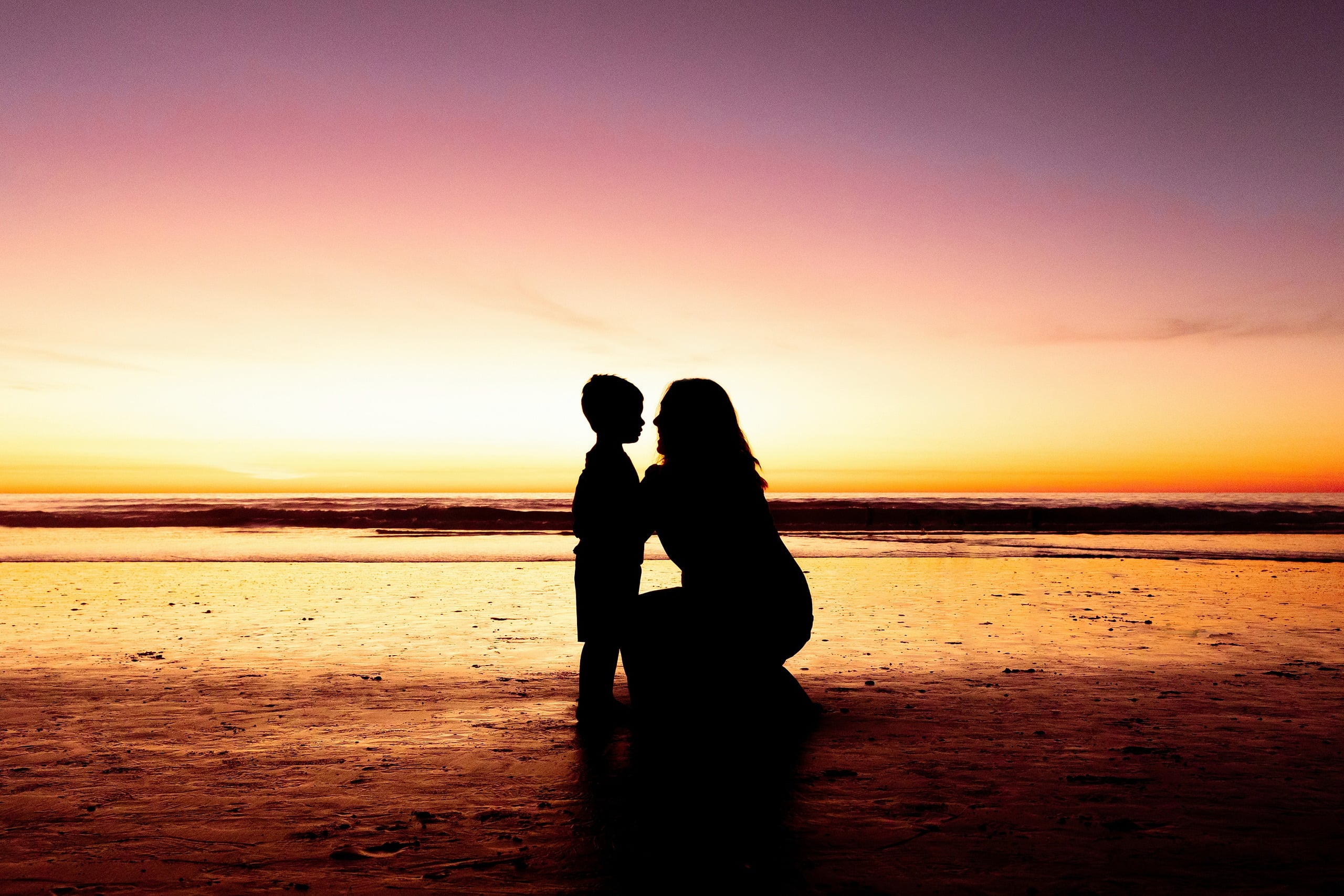 The Day the Sun Stood Still — 35 Woman holding child in silhouette at sunset on Del Mar beach