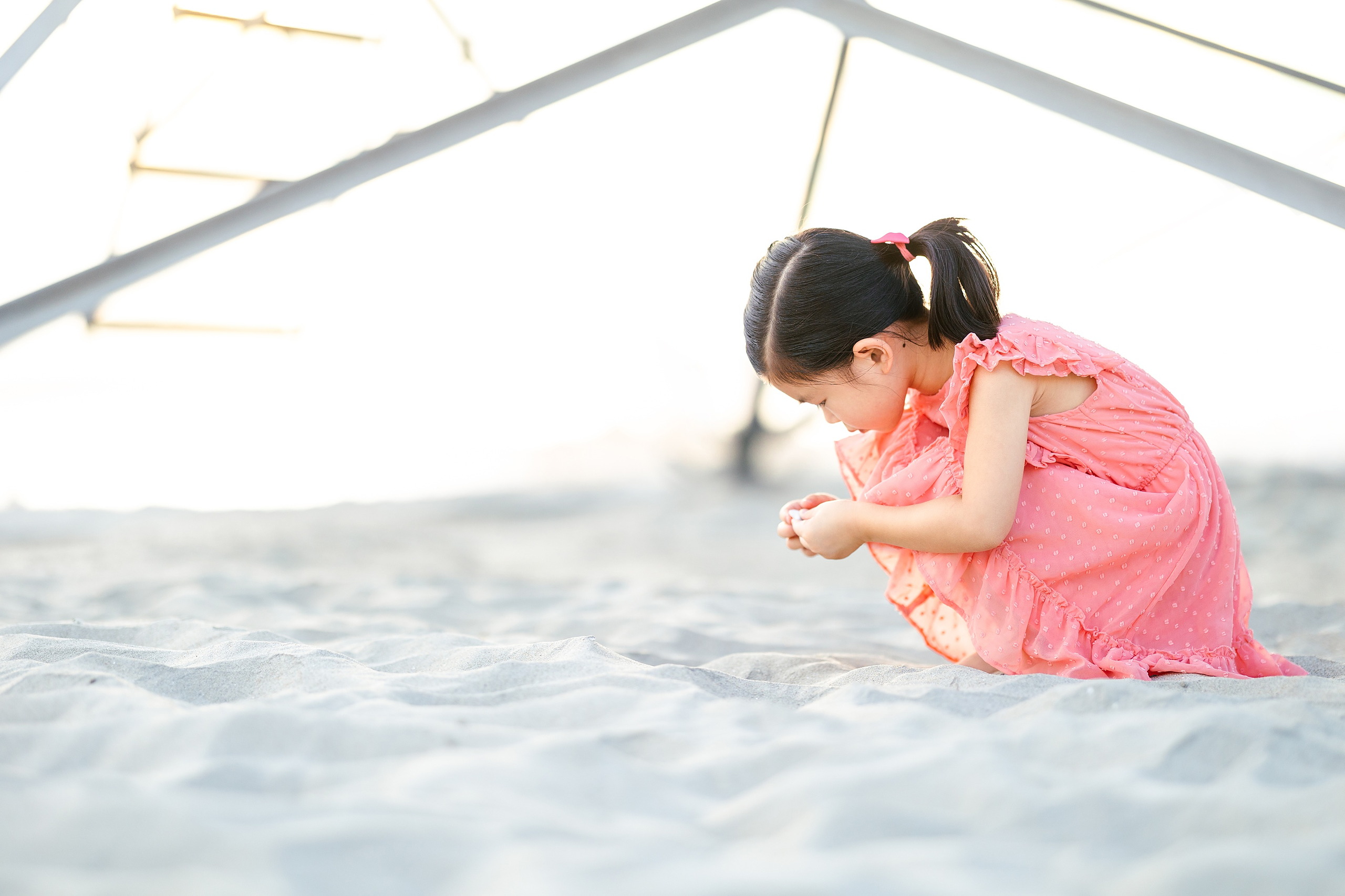 Turning Five on Coronado — 06 Ava crouching near sand dunes with Hotel del Coronado structure in background