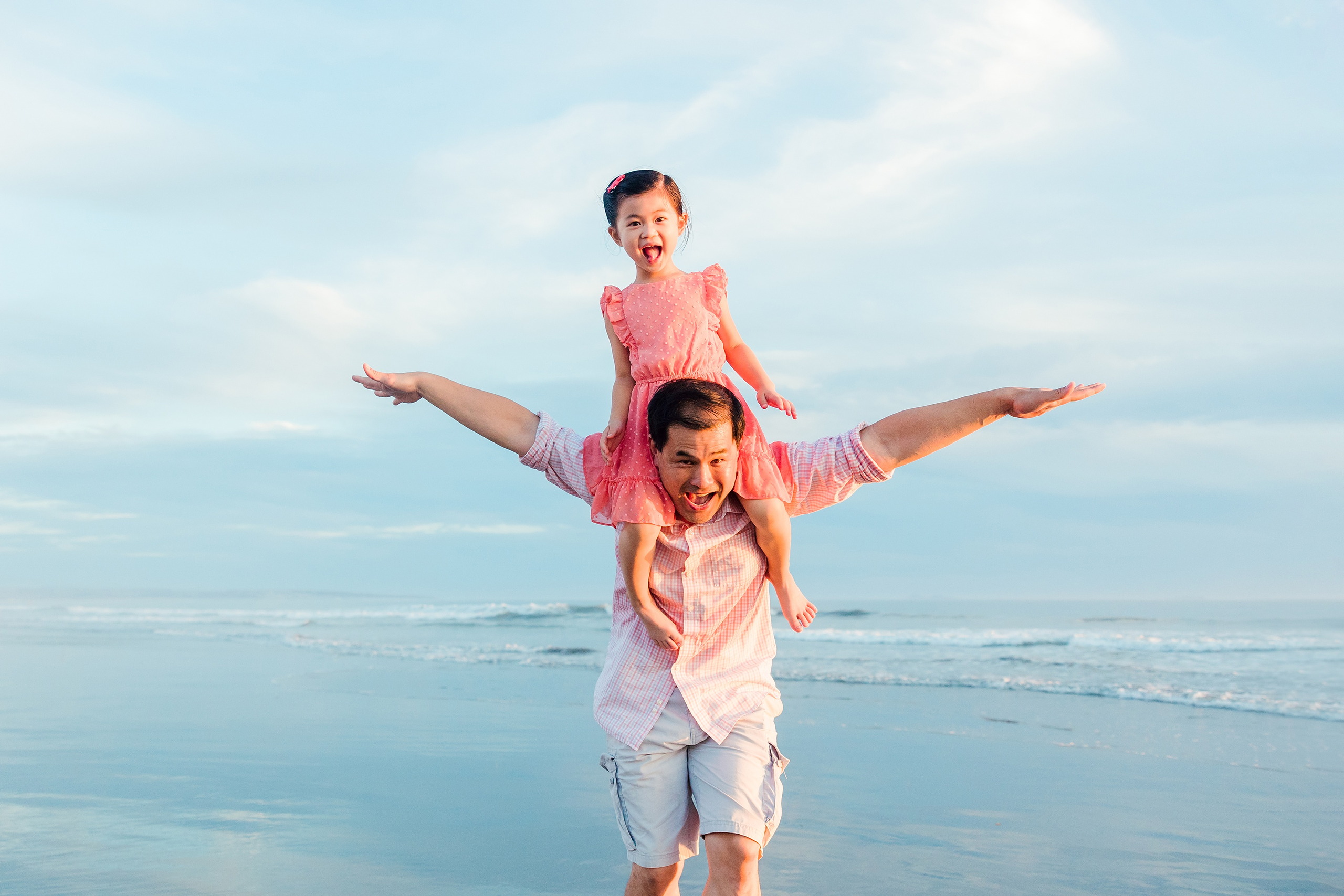 Turning Five on Coronado — 25 Ava on dad's shoulders with arms raised in shallow water at beach