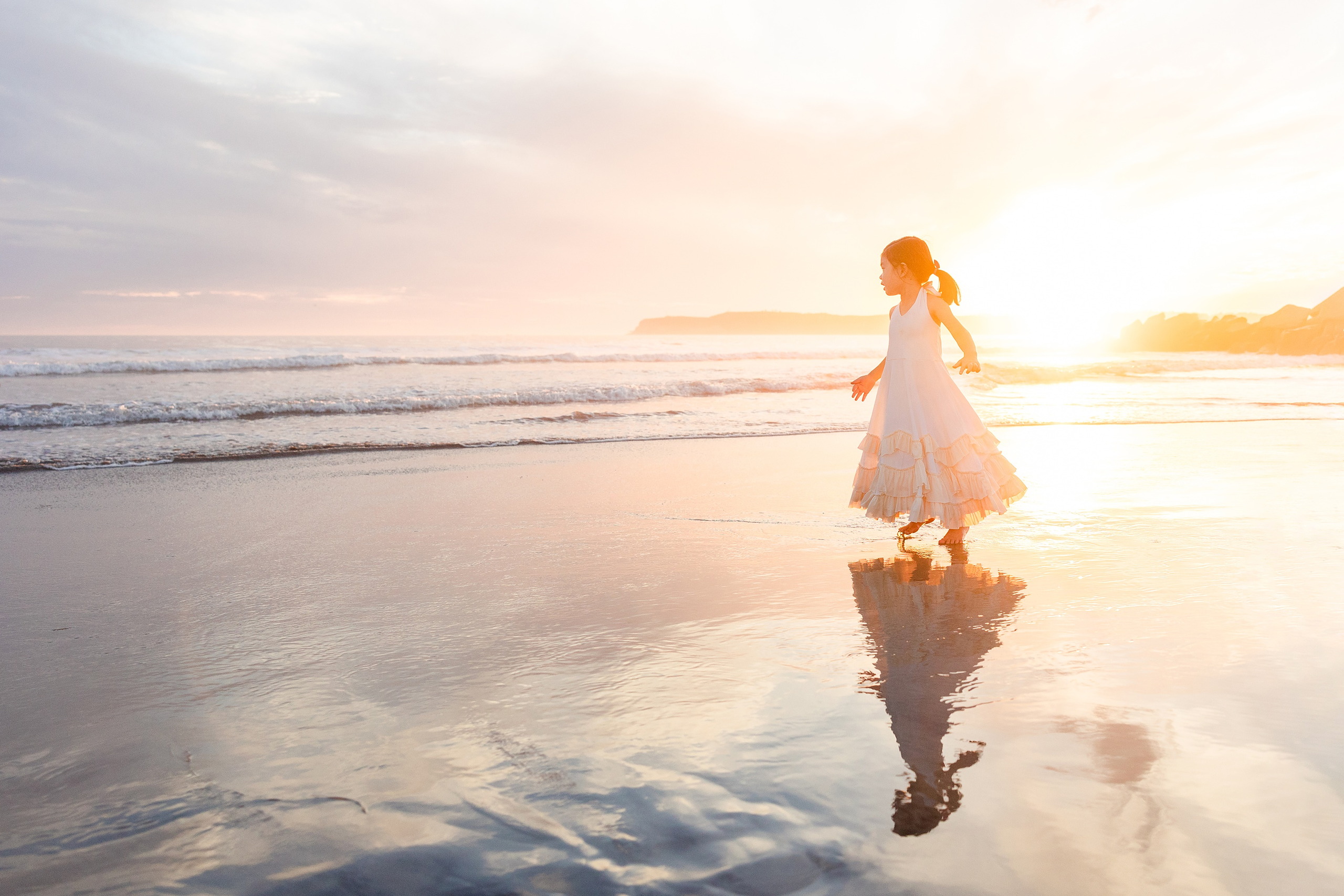 Turning Five on Coronado — 26 Ava standing in shallow water at sunset with golden hour lighting