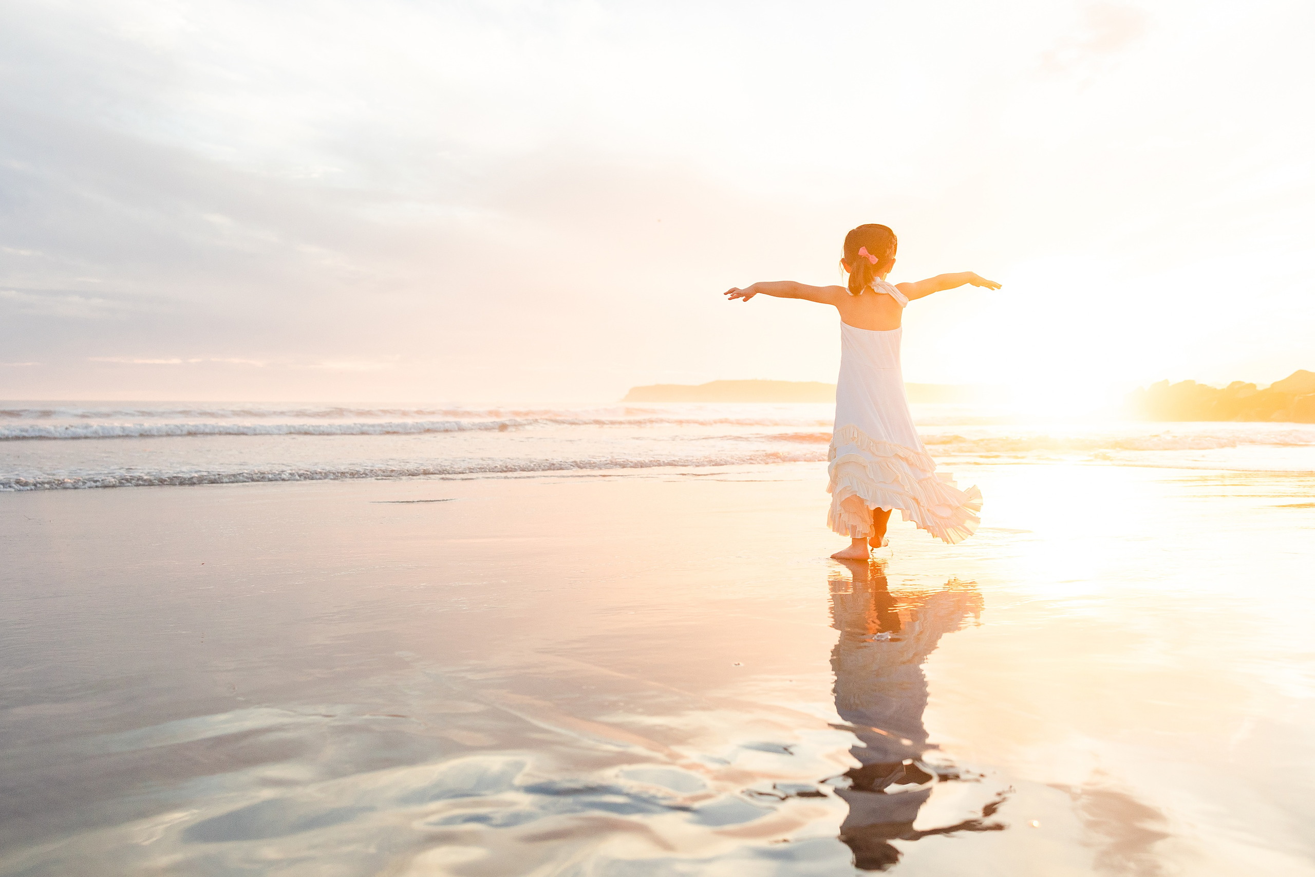 Turning Five on Coronado — 27 Ava with arms outstretched in shallow water at golden hour on beach