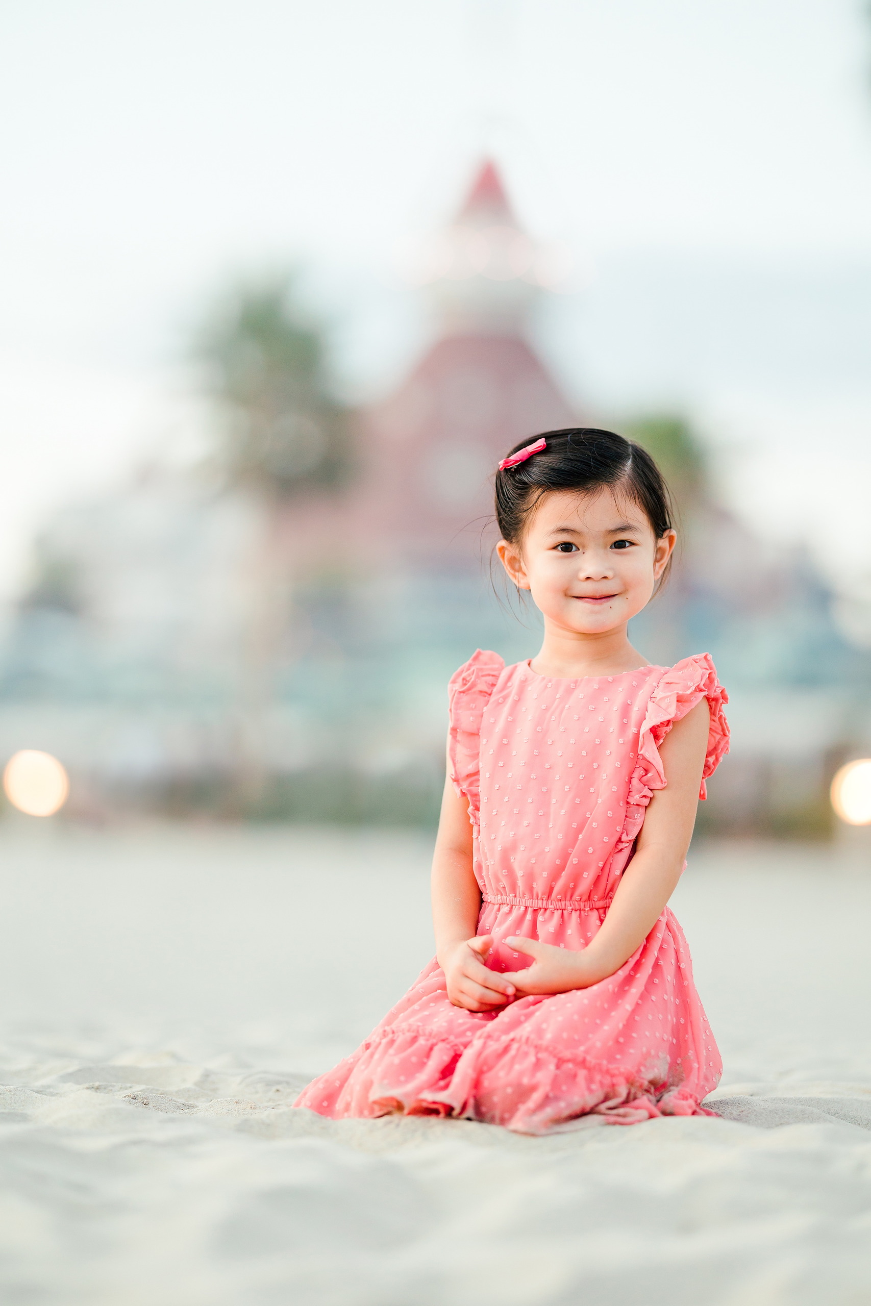 Turning Five on Coronado — 34 Ava sitting on sand near water with Hotel del Coronado tower out of focus