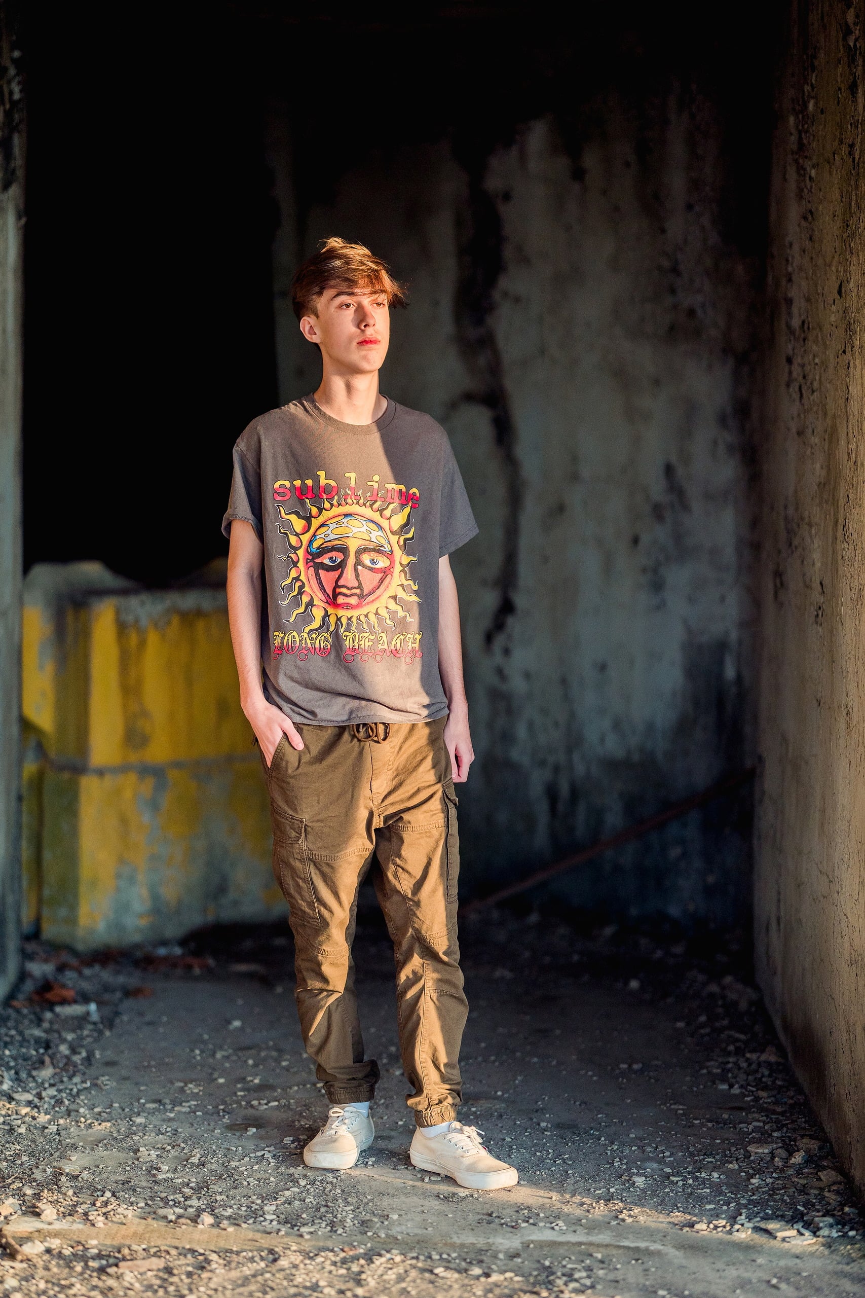 Zach’s Senior Portraits — 05 Zach standing in shadowed tunnel wearing gray Sublime shirt