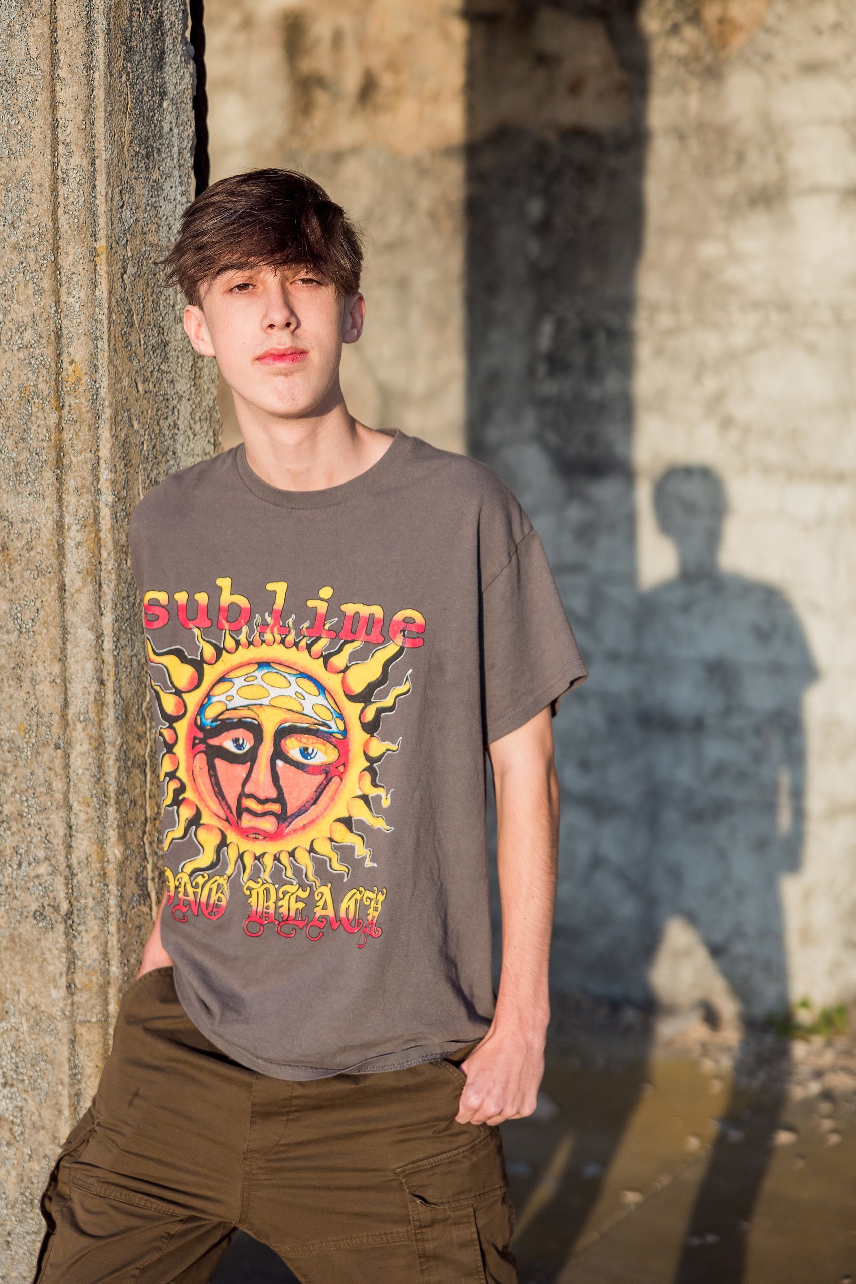 Zach’s Senior Portraits — 10 Zach standing with shadow on wall, serious expression at Fort Monroe