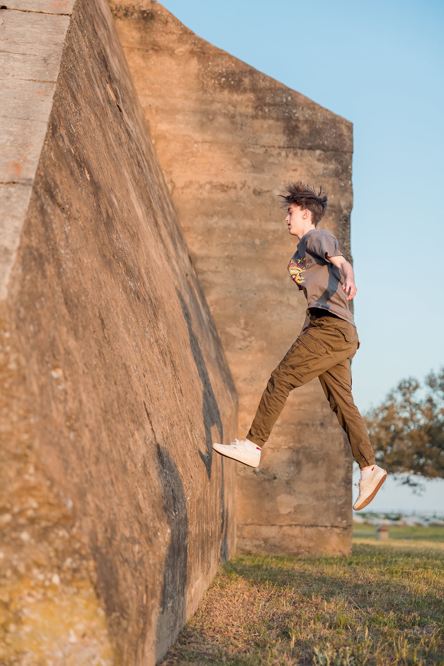 Zach’s Senior Portraits — 16 Zach jumping on weathered brick wall during dynamic motion at battery