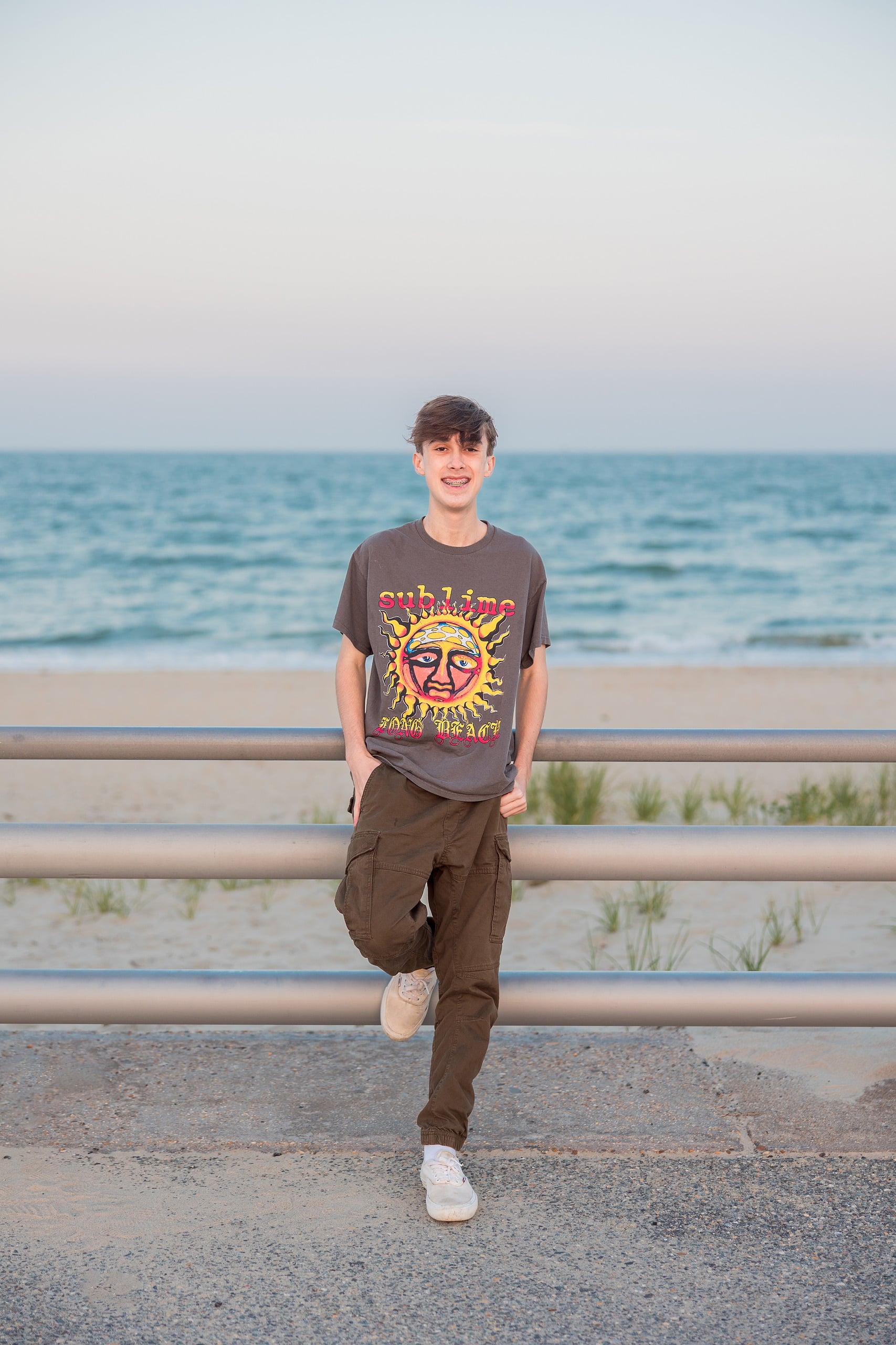 Zach’s Senior Portraits — 26 Zach in graduation gown on beach with kite flying in clear sky