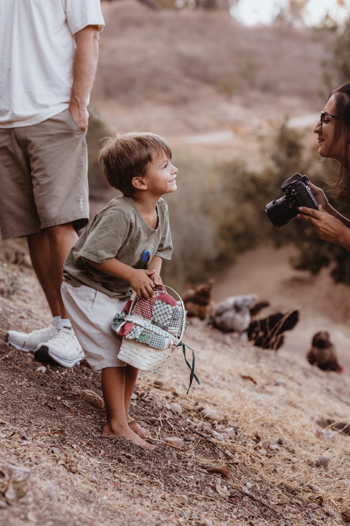 Little boy in cape gazes up at dad on hillside trail