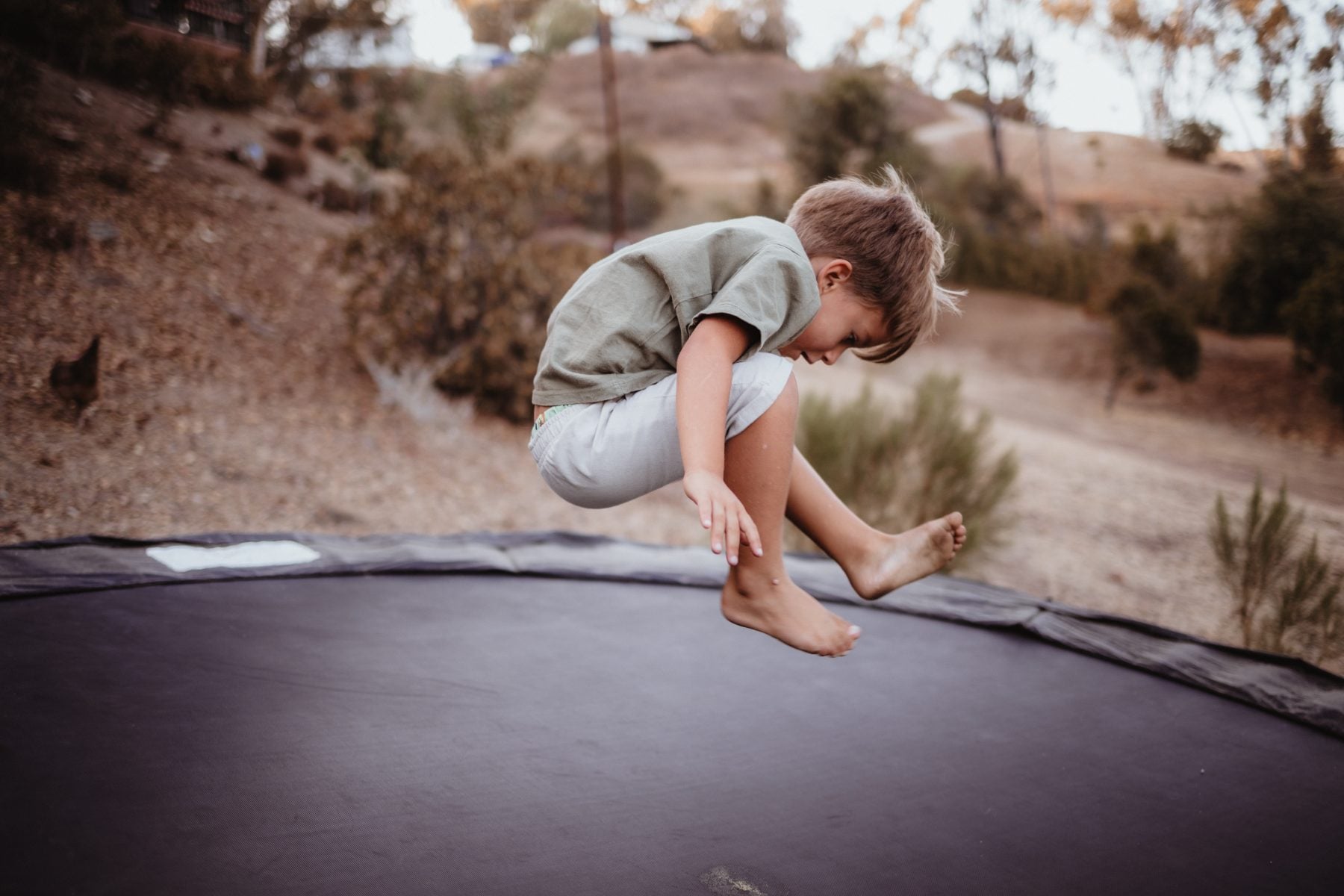 Barefoot boy jumps mid-air on backyard trampoline in Lakeside, California