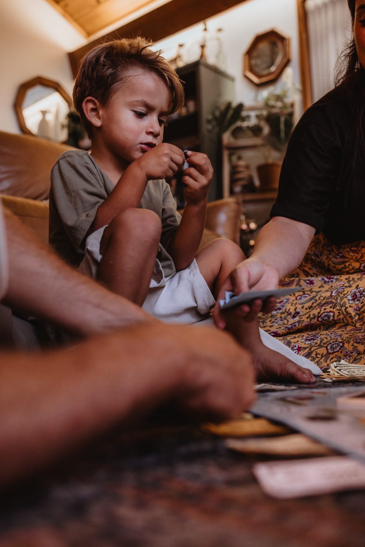 Boy focuses on a card game while family gathers around him indoors