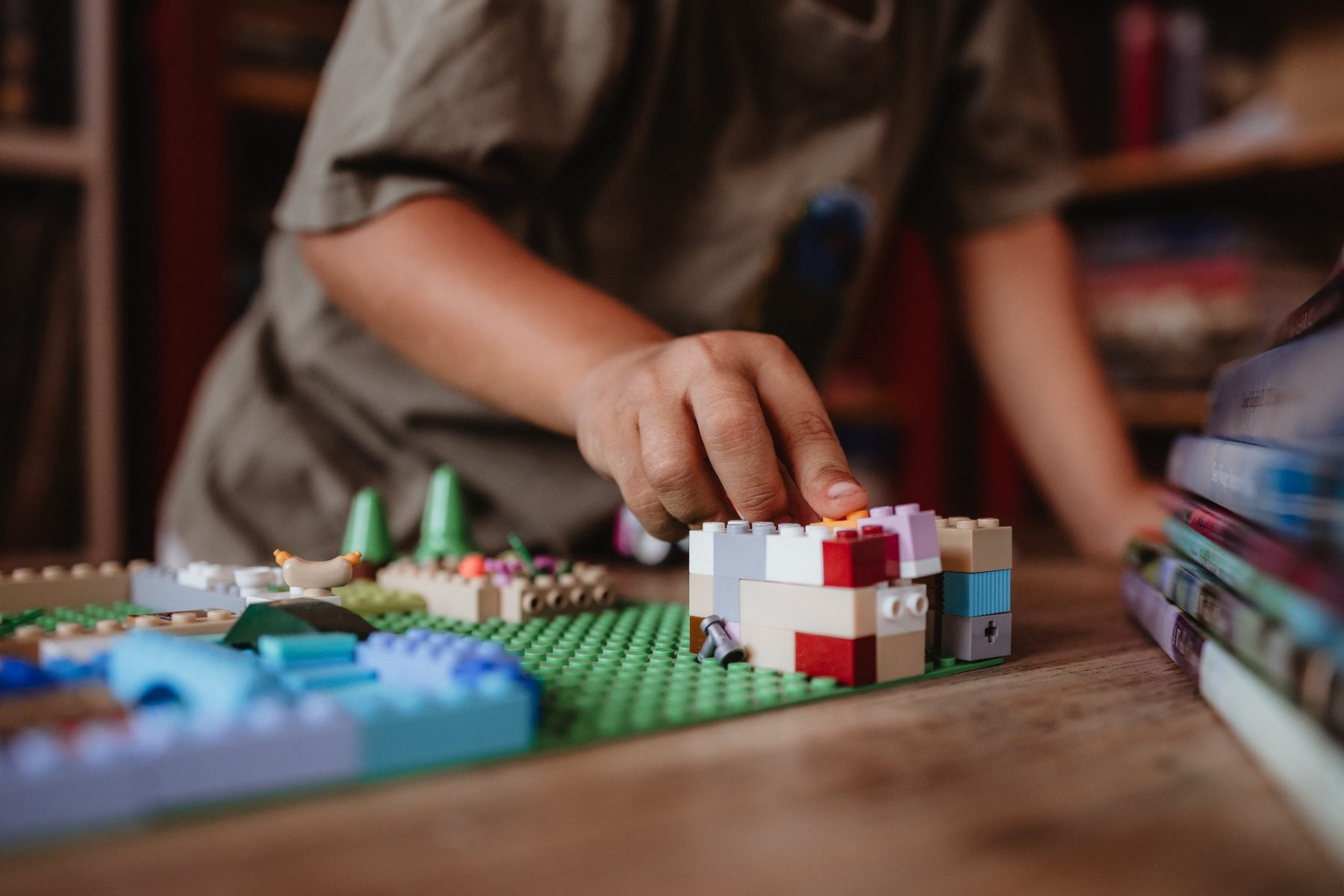 Child's hands building with colorful Lego bricks on wooden table