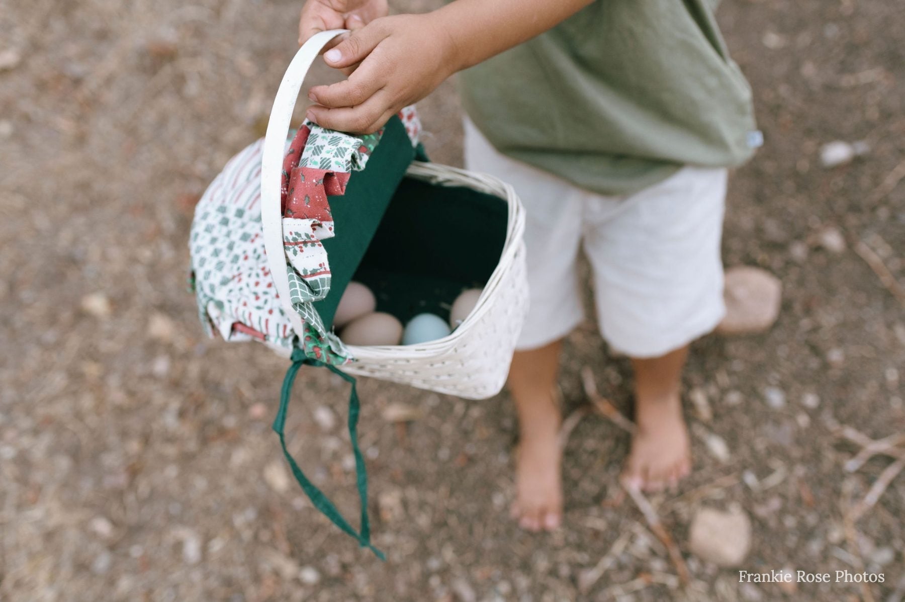 Child's hands holding a fabric Easter basket filled with colorful eggs