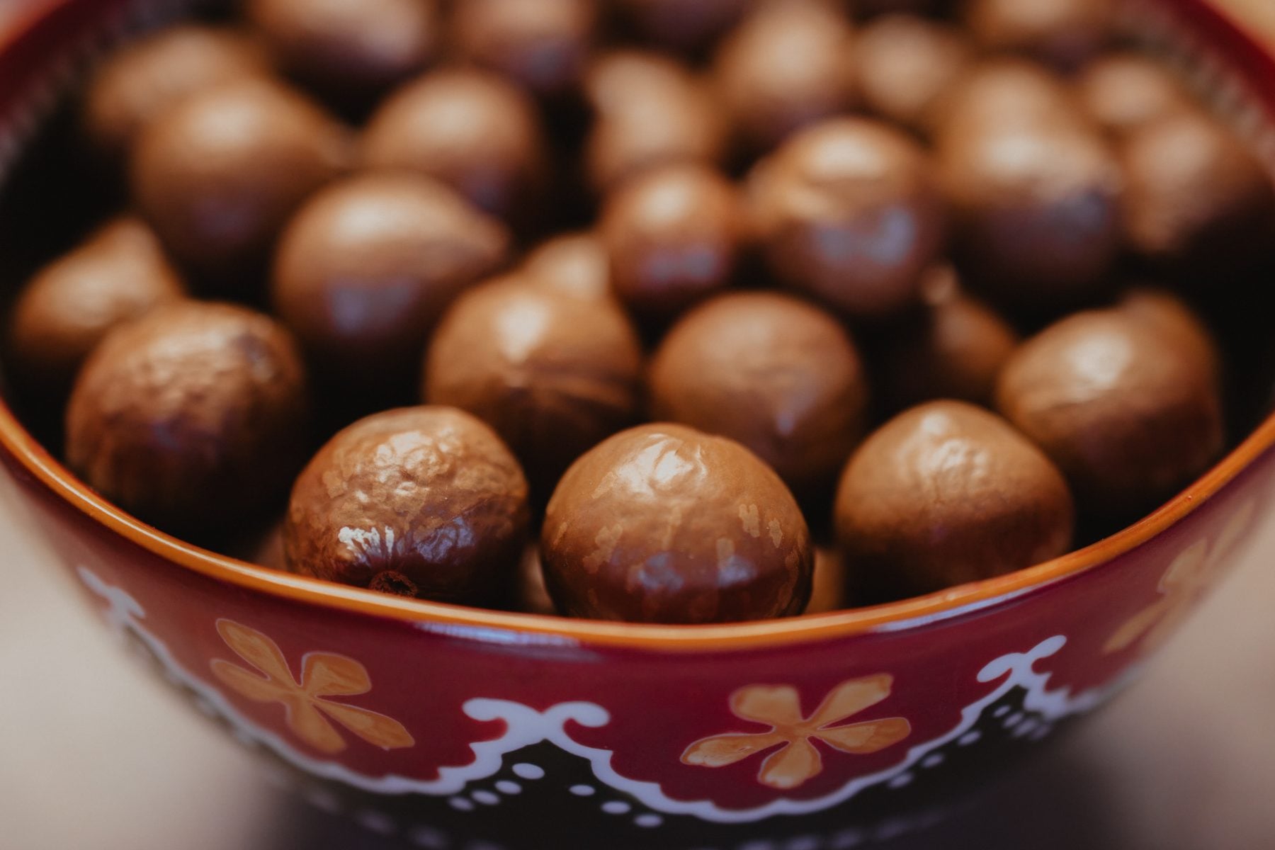 Close-up bowl of glossy chocolate malt balls in decorative red dish