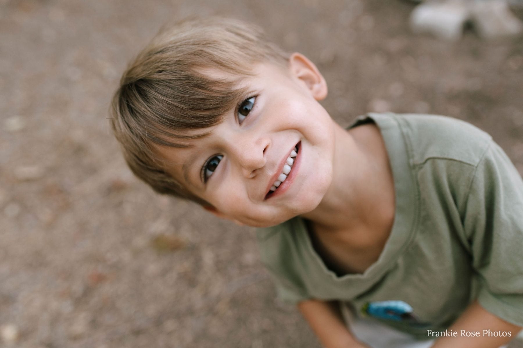 Close-up of smiling boy with tousled hair looking up at camera