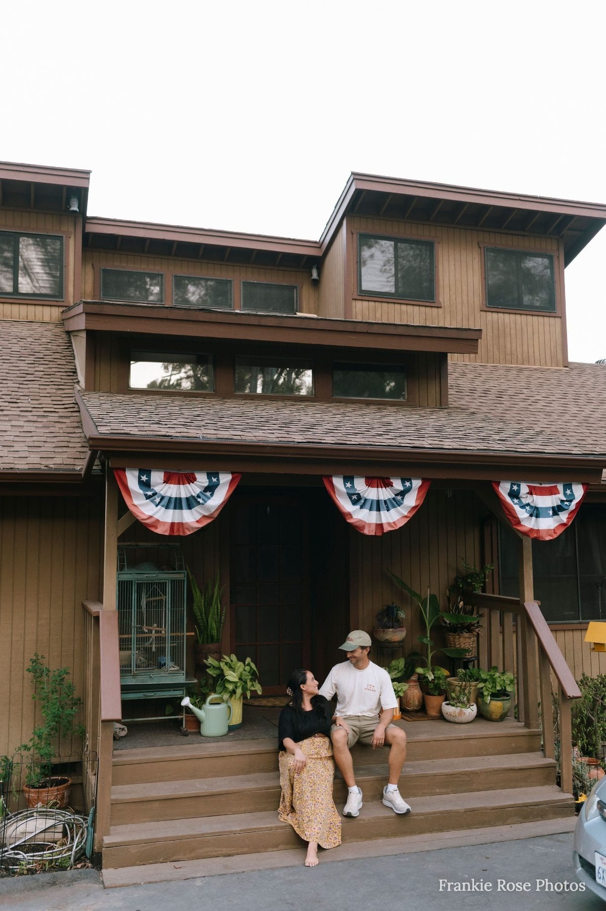 Couple sits together on wooden porch steps decorated with patriotic bunting