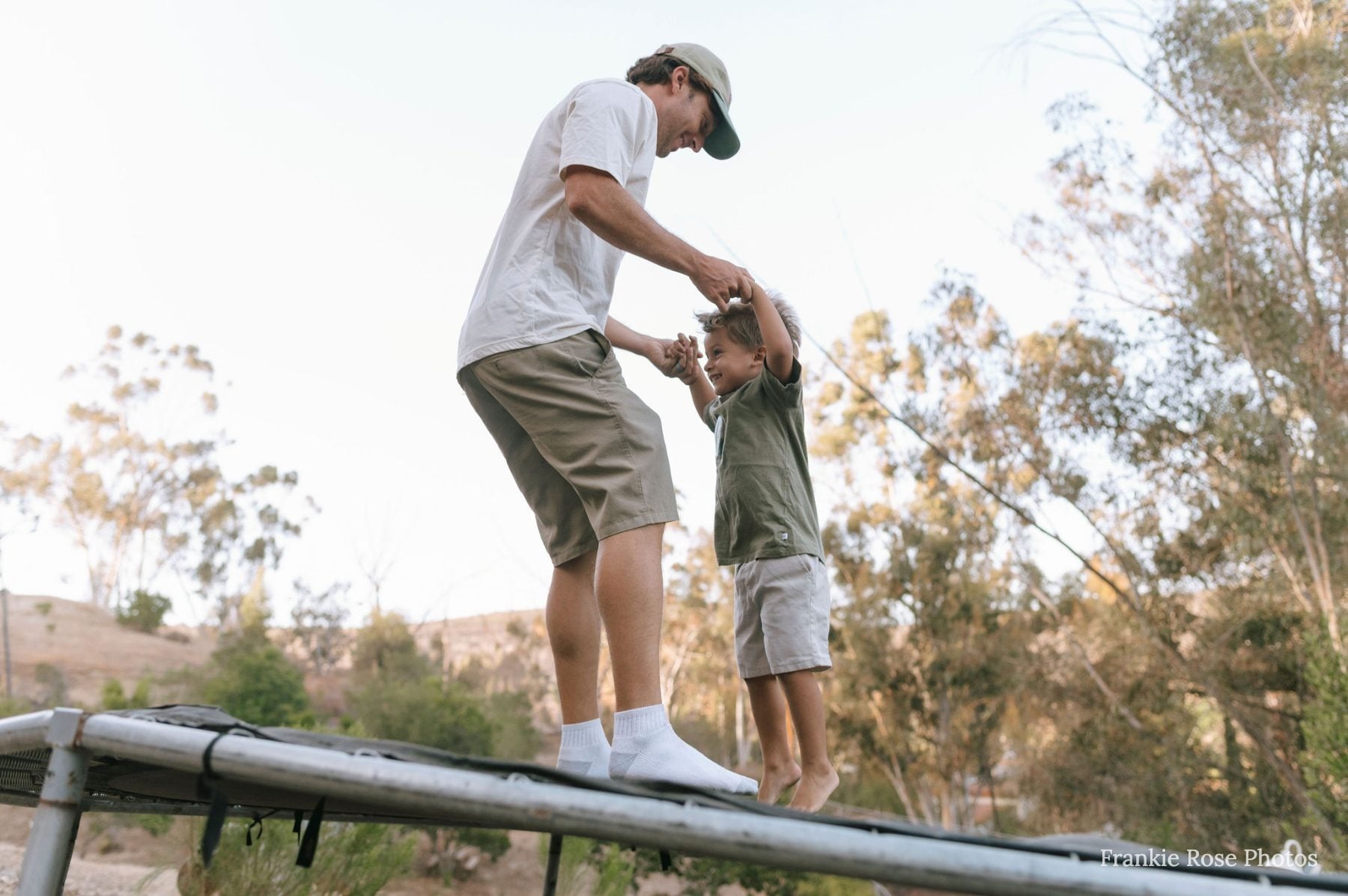 Dad and son share a moment together while standing on a trampoline