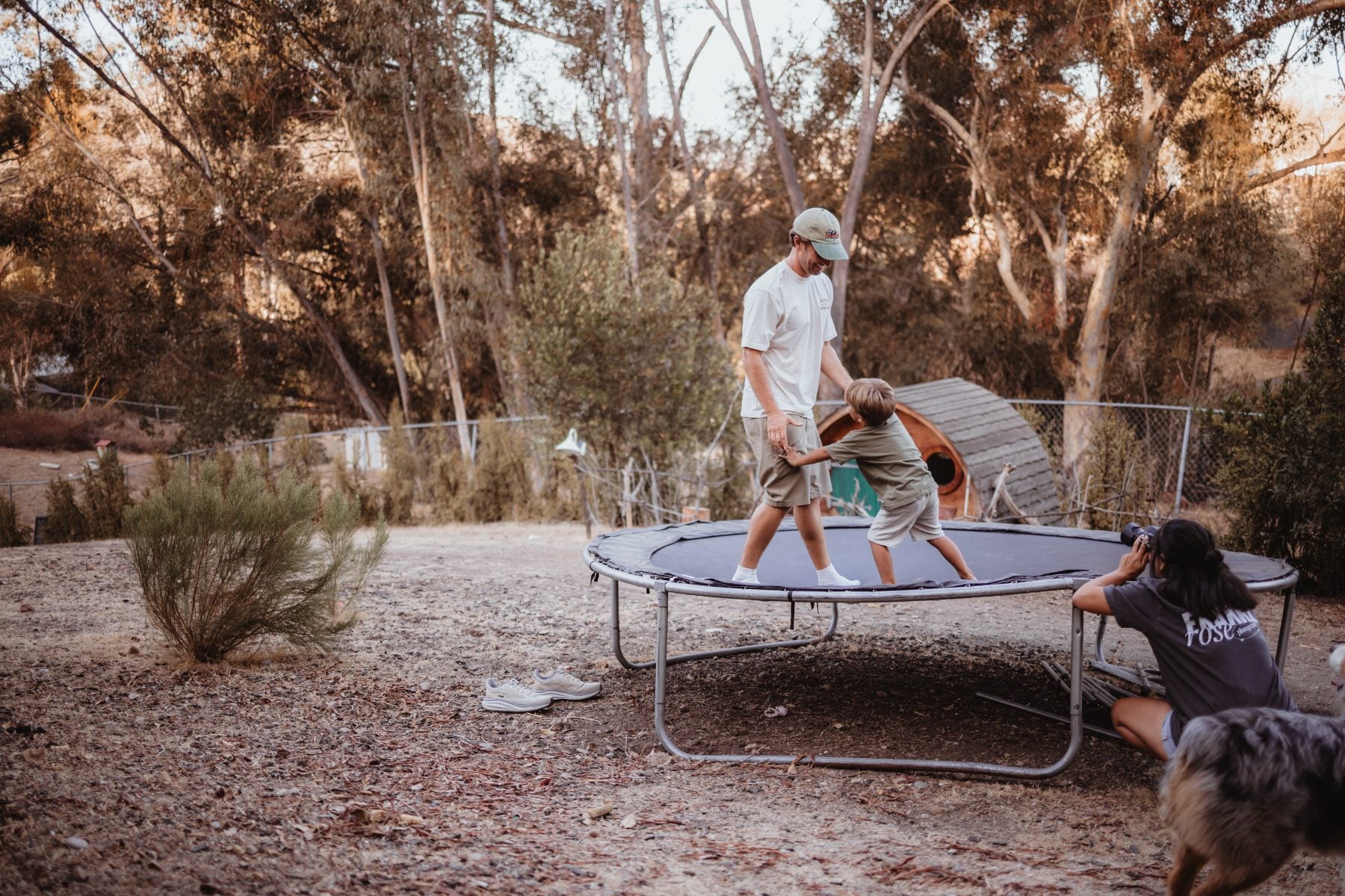 Dad helps two kids bounce on a backyard trampoline in Lakeside