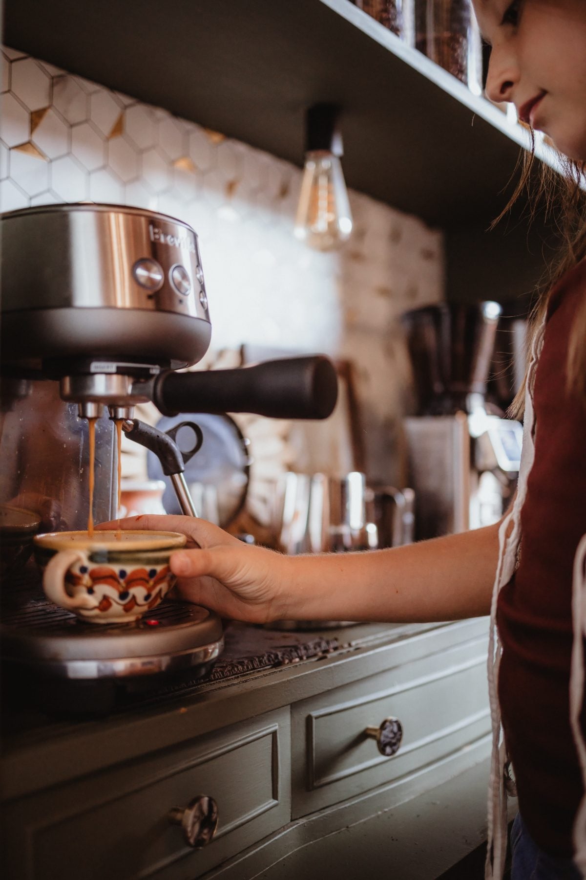 Woman pulls espresso shot from machine in Lakeside kitchen