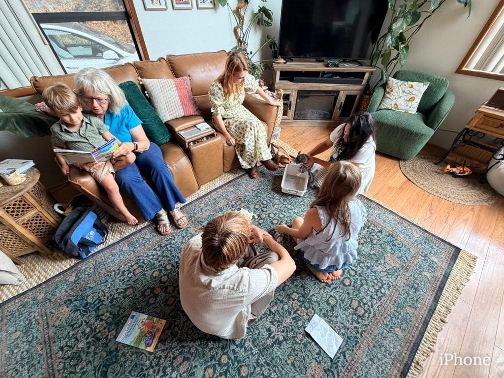 Extended family gathers on rug and couch reading together in Lakeside living room