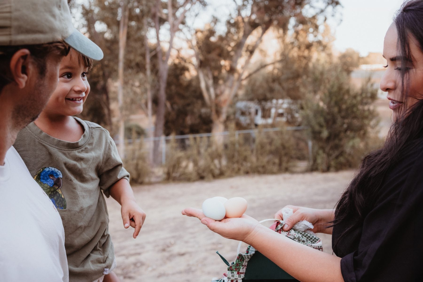 Boy and parents admire fresh eggs held by woman outdoors