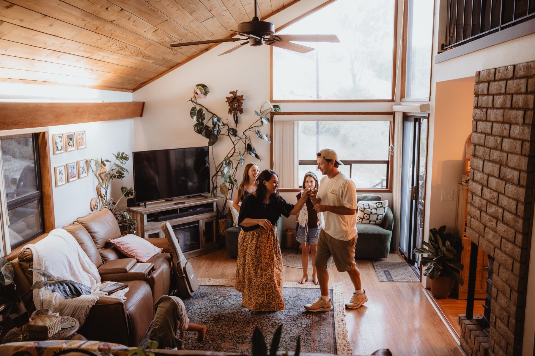 Family dances together beneath vaulted wood ceilings in their Lakeside living room
