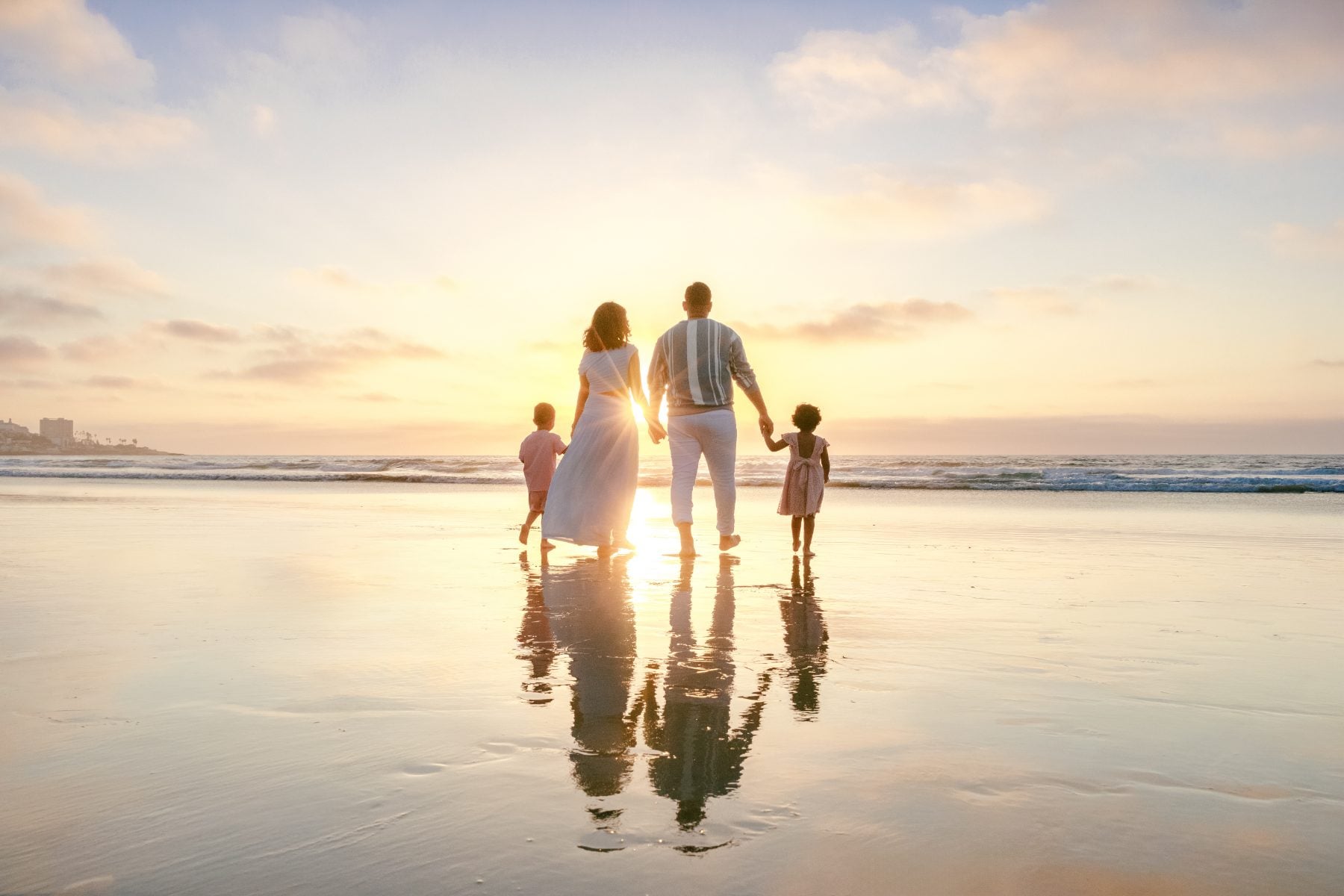 Family of four faces the ocean, holding hands at golden hour, La Jolla Shores