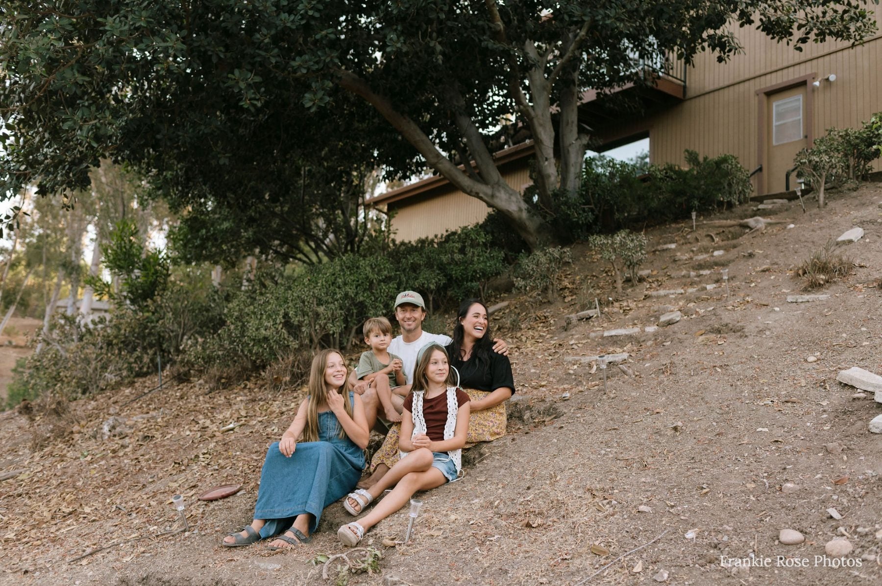 Family of five sitting on a dirt hillside near their Lakeside home