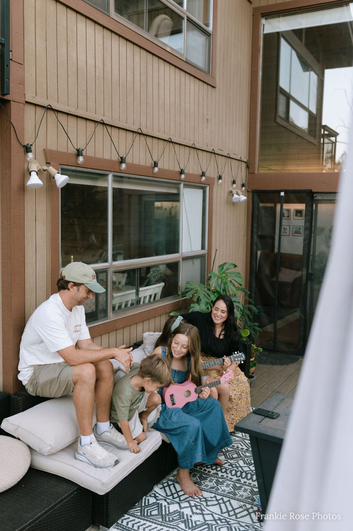 Parents and two kids relax on an outdoor patio bench at home