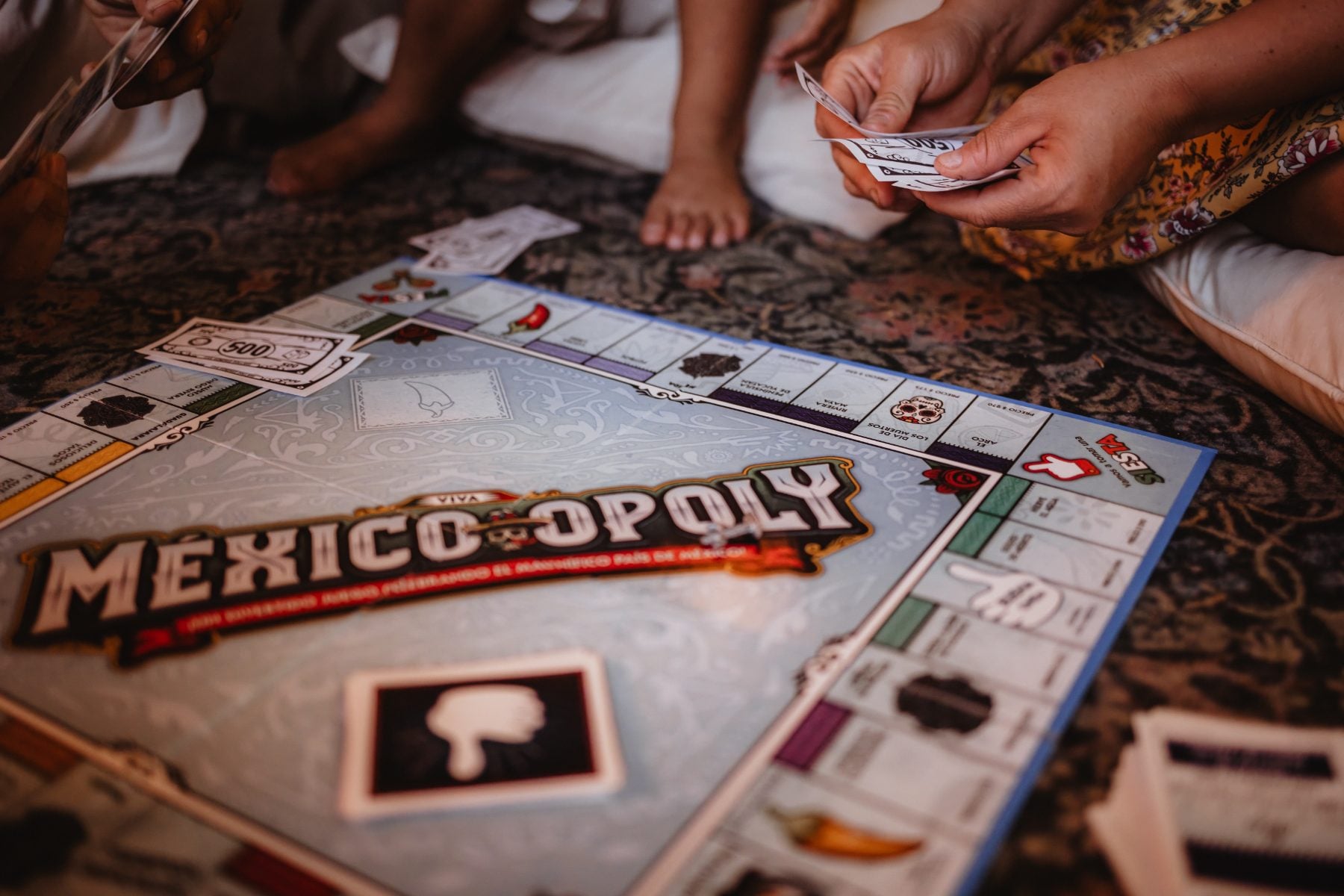 Family plays Mexico-opoly board game seated on patterned living room rug