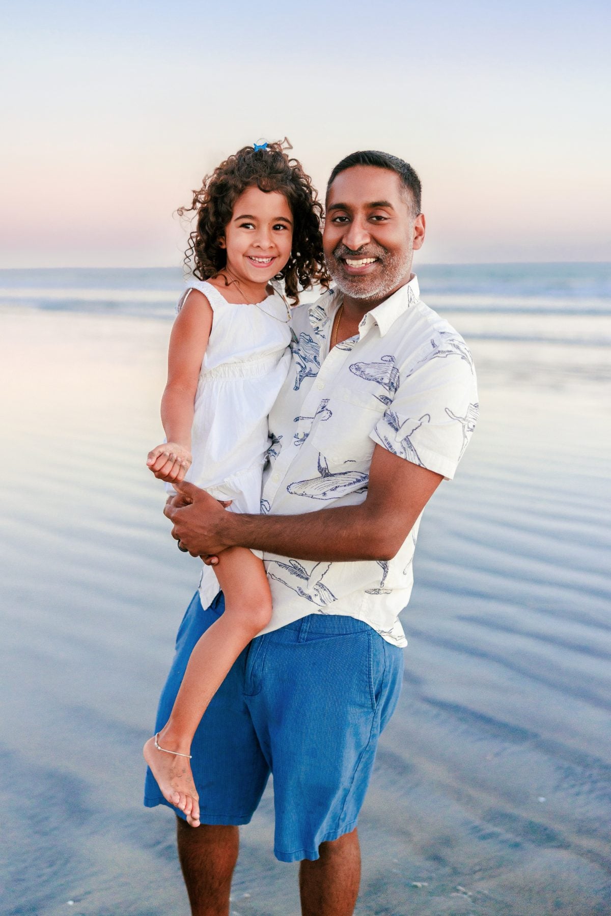 Dad holding his smiling daughter on the sand at Coronado Beach