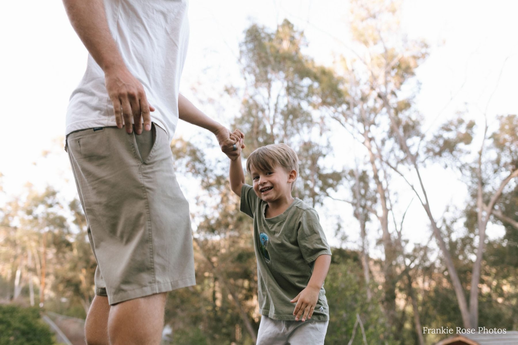 Father and laughing son hold hands walking outside in Lakeside, California