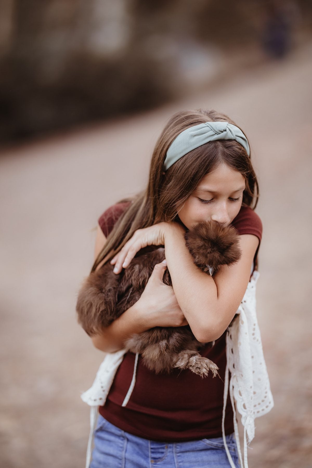 Young girl in maroon top hugs a fluffy dog outdoors in Lakeside