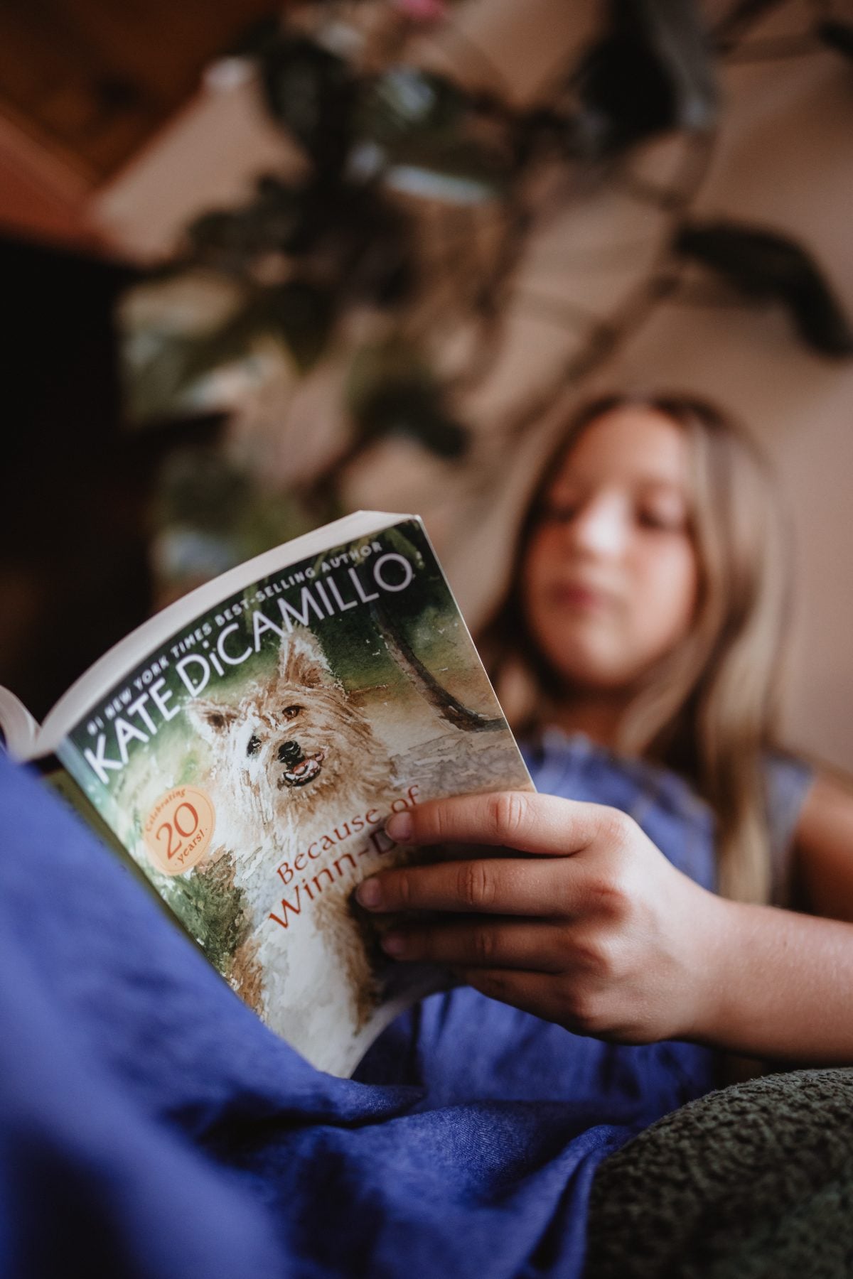 Girl reads Because of Winn-Dixie curled up on a couch