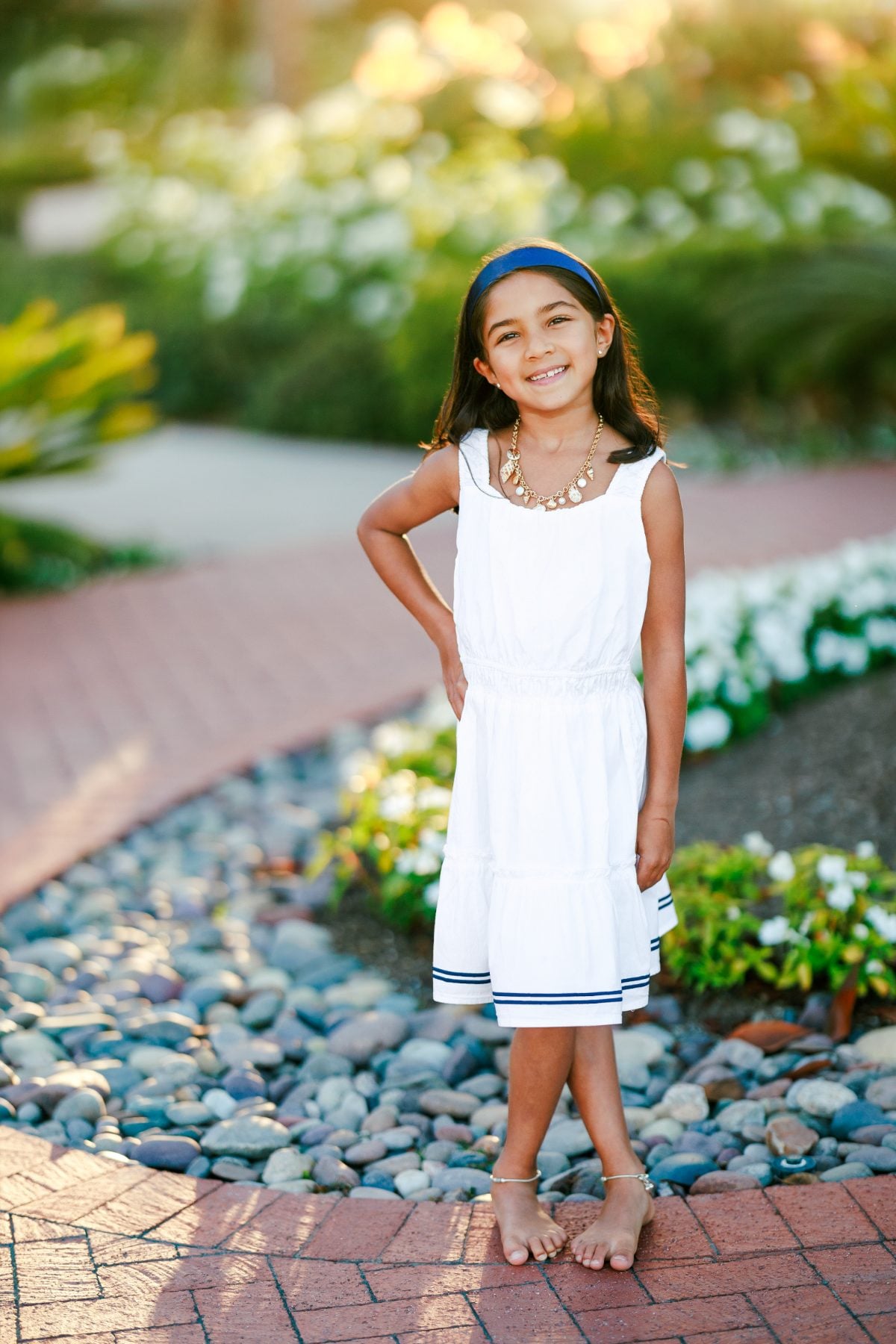 Young girl in white dress smiling on a stone path at Hotel del Coronado