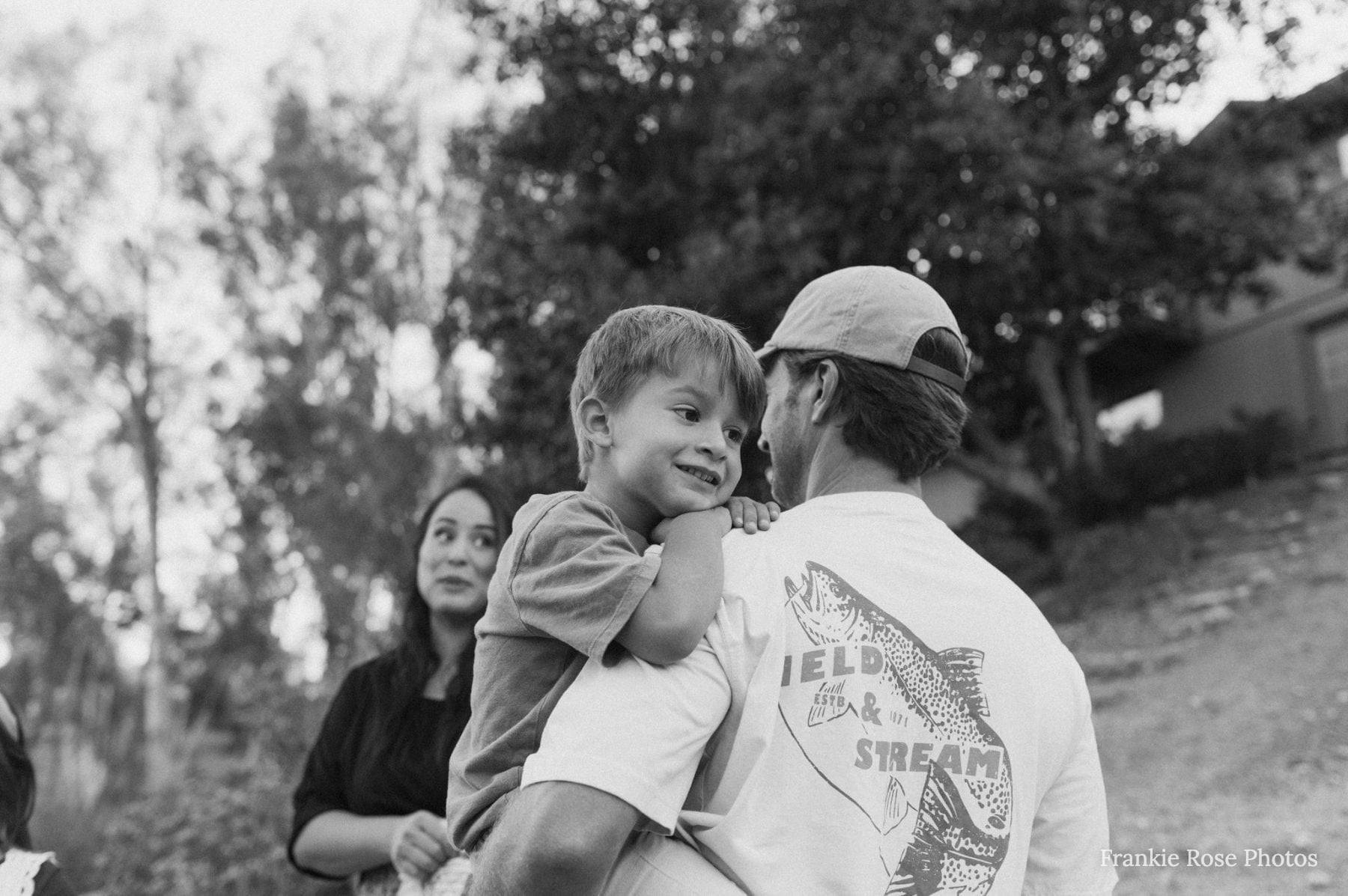 Grandmother watches as dad holds young son outside their Lakeside home