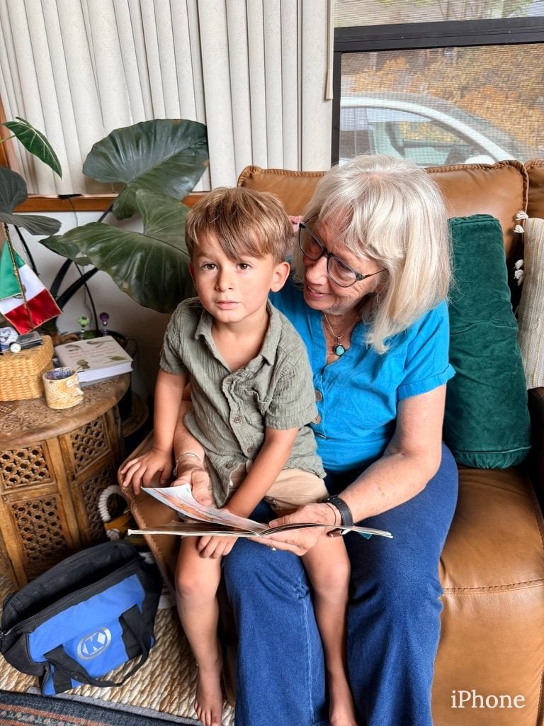 Grandmother reads a book with young grandson on cozy leather couch