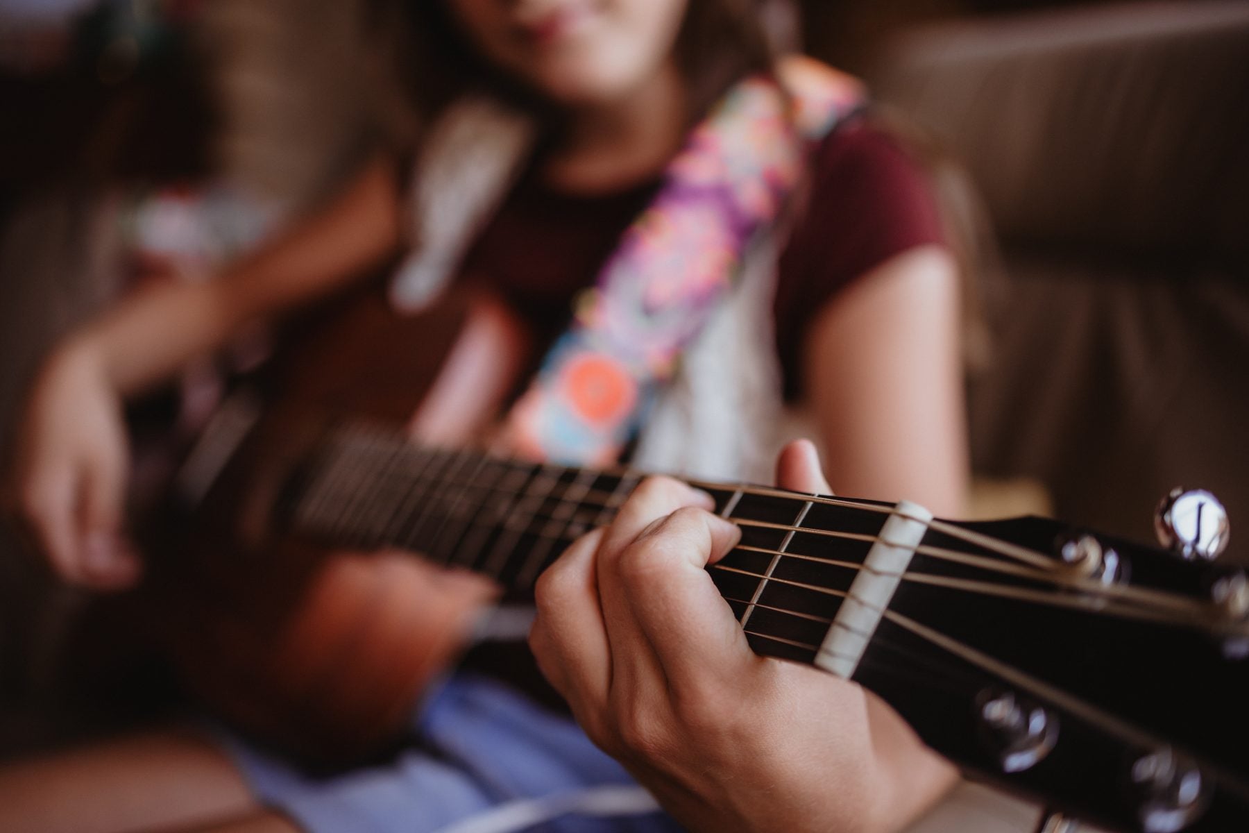 Close-up of hands playing acoustic guitar on a couch in Lakeside home