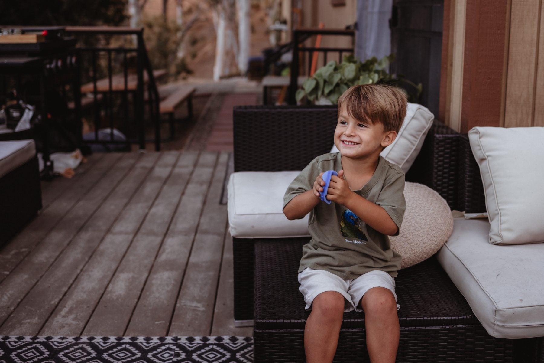 Young boy laughs while relaxing on patio couch, Lakeside home