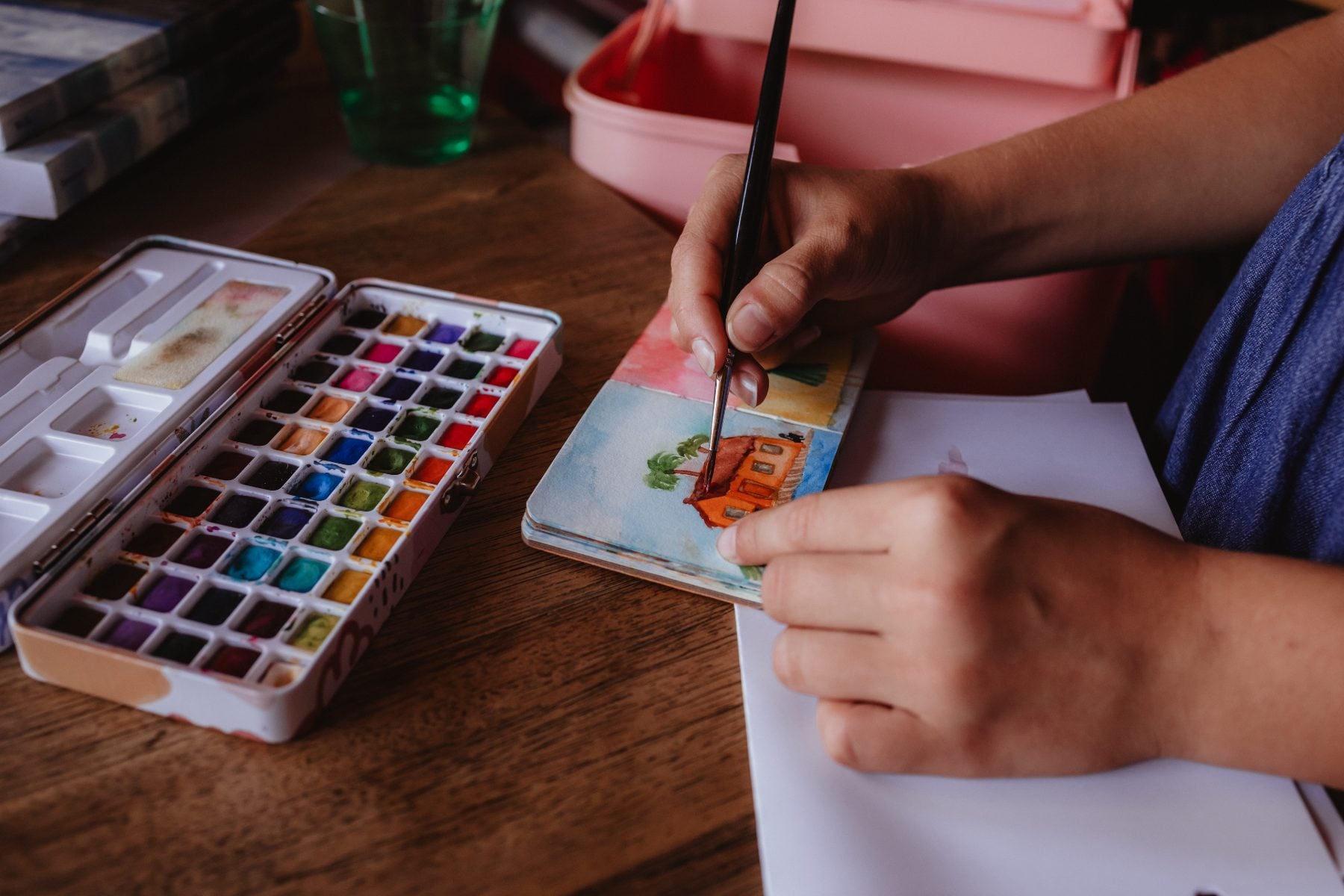 Artist paints a house scene using watercolor palette