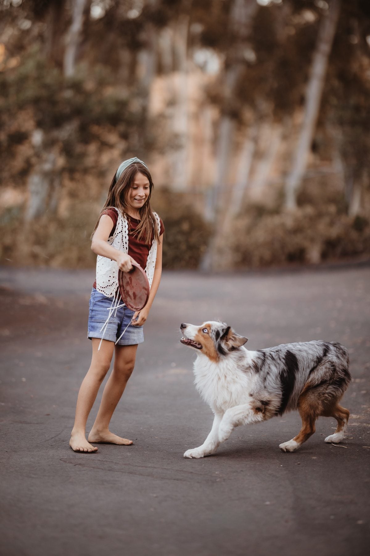 Girl stands smiling as the family dog approaches her in Lakeside