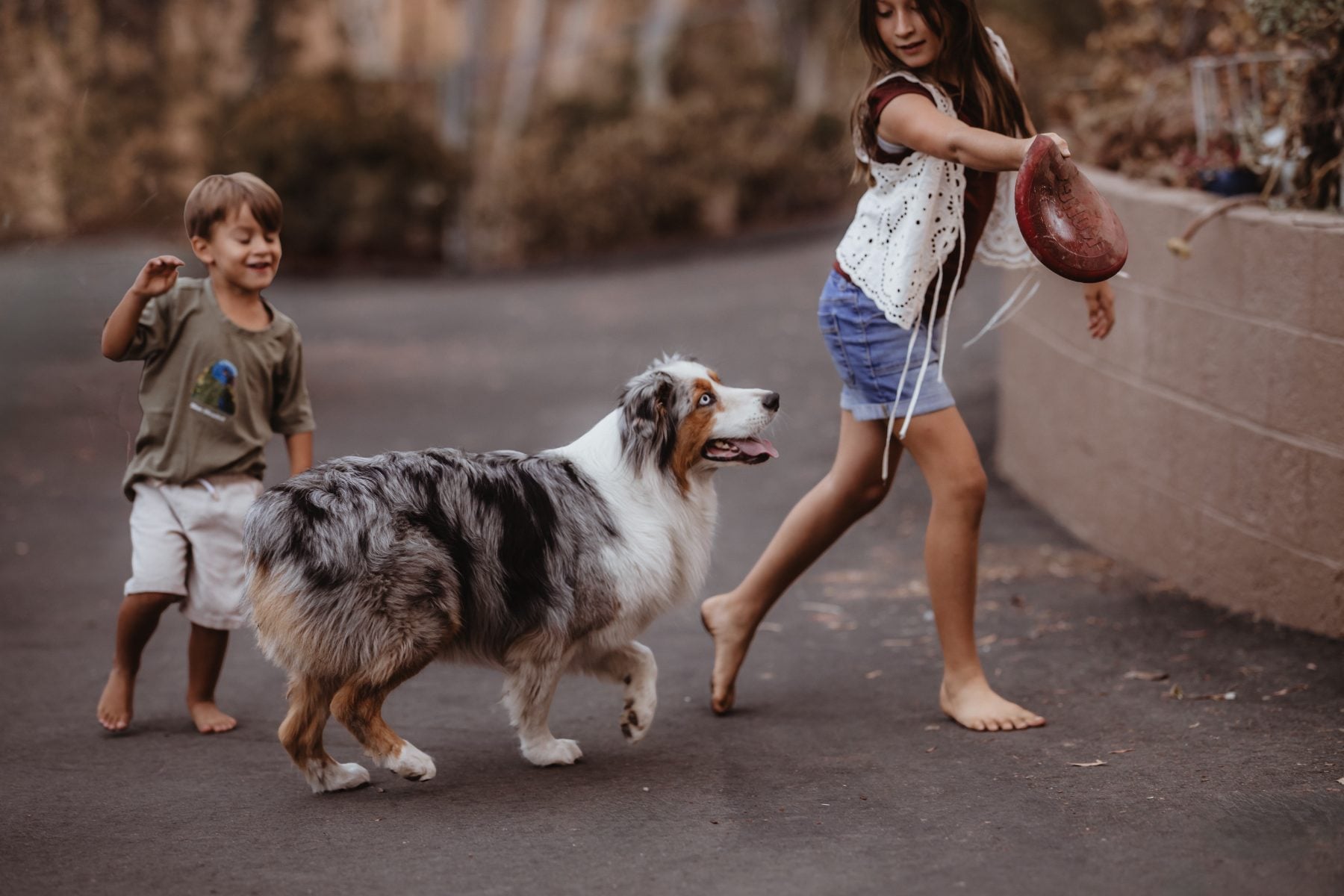 Brother and sister walk with their dog down a Lakeside street