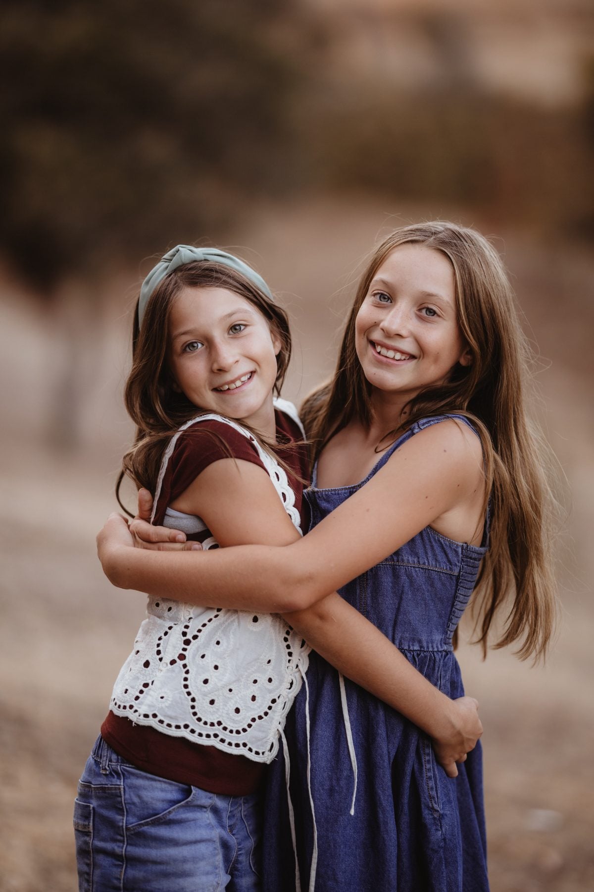 Two sisters hug and smile together outdoors in Lakeside, California