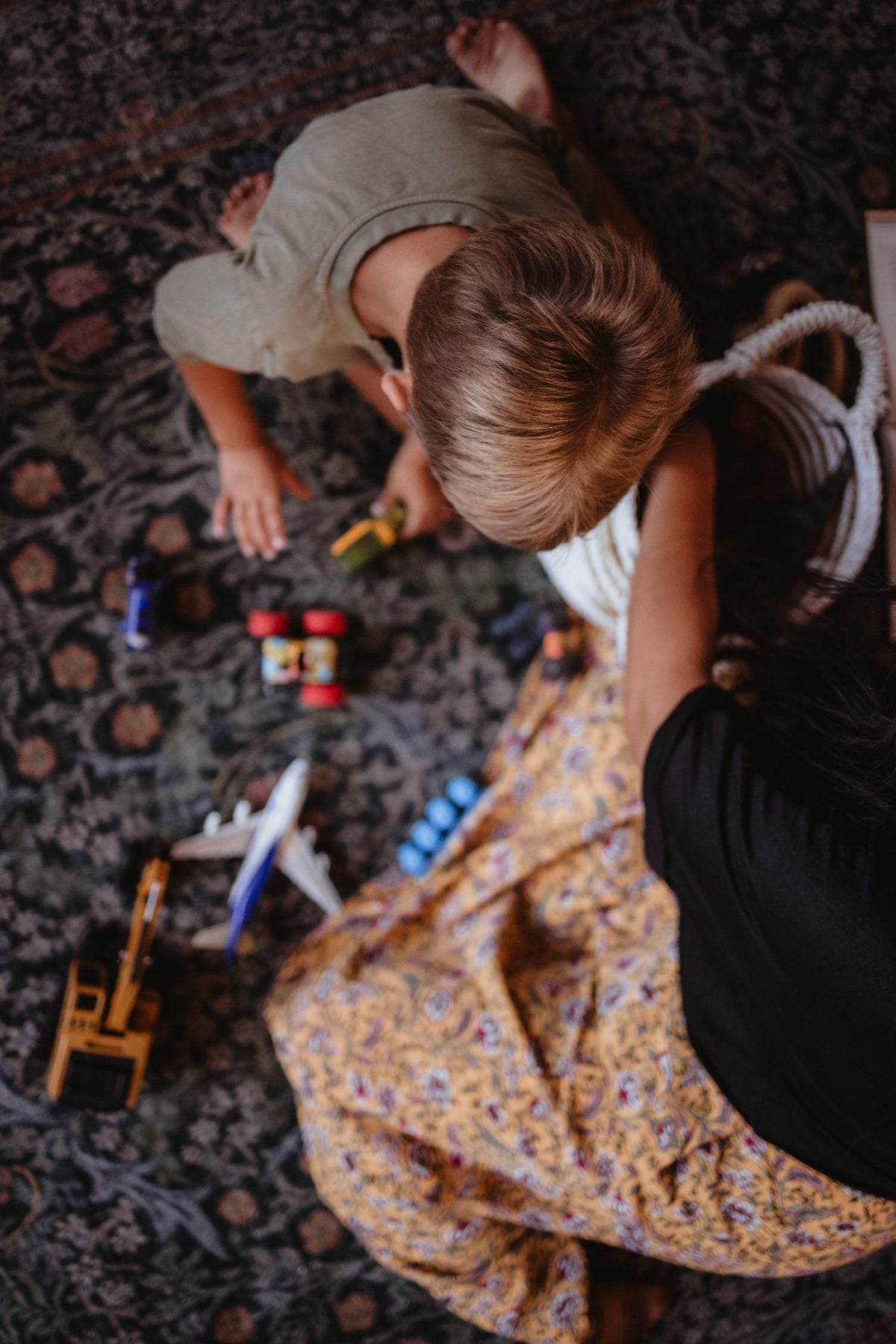 Overhead view of siblings playing with toy cars on rug