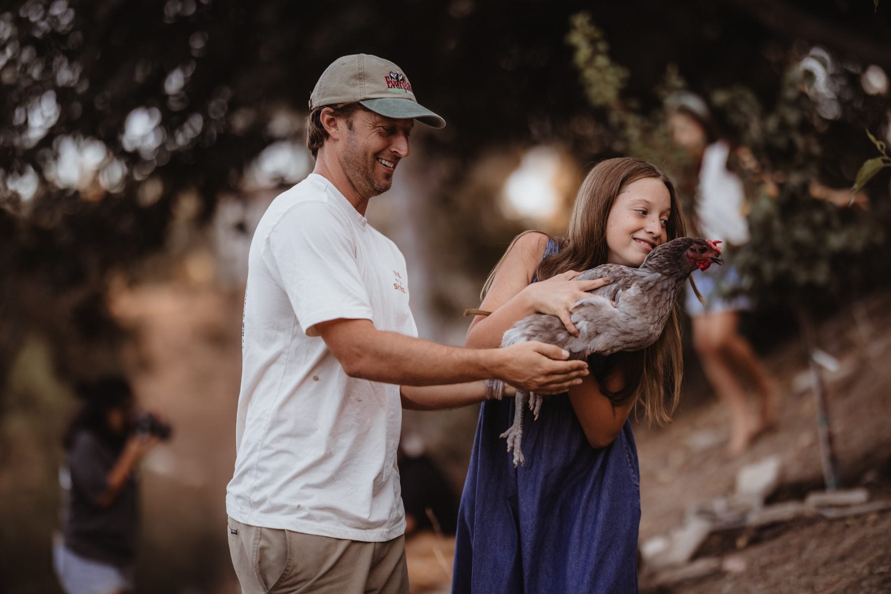 Father and daughter smile while holding a chicken together, Lakeside